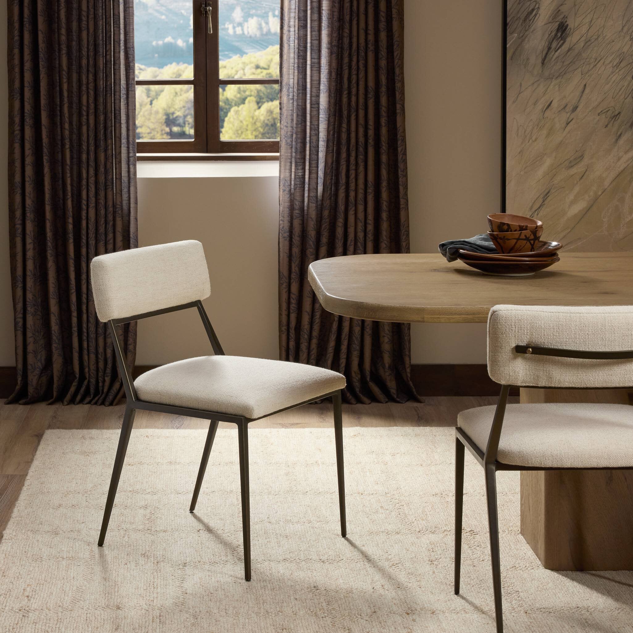 Dining room with beige chairs and a wooden table near a window with curtains.