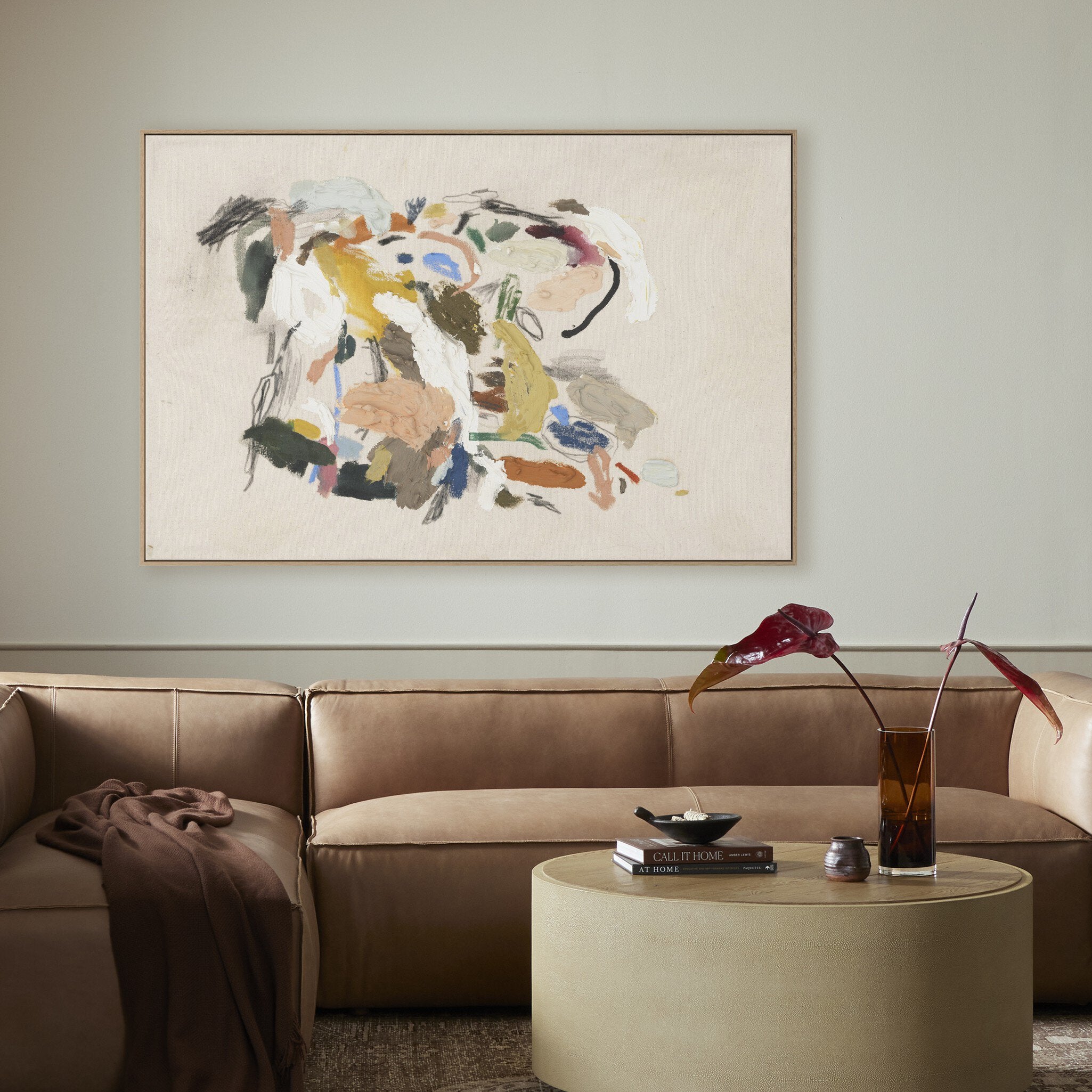 Living room with a brown sofa, round coffee table, and abstract painting on the wall.