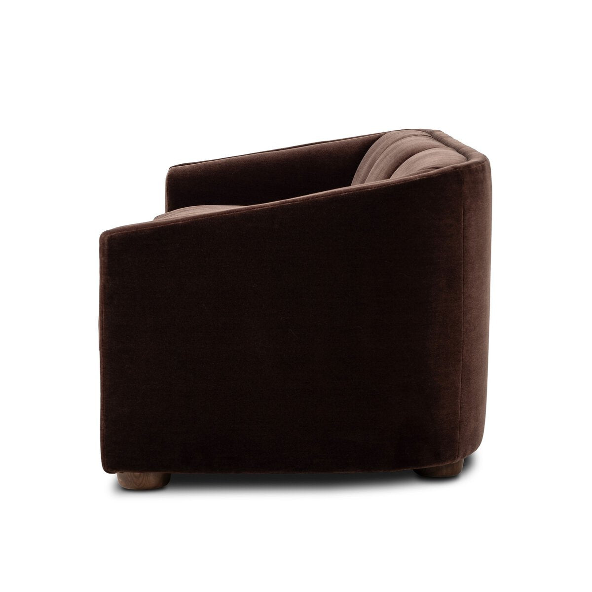 A dark brown velvetsofa with a rounded rectangular silhouette and tufted back cushions, shown from a three-quarters angle on a white background.