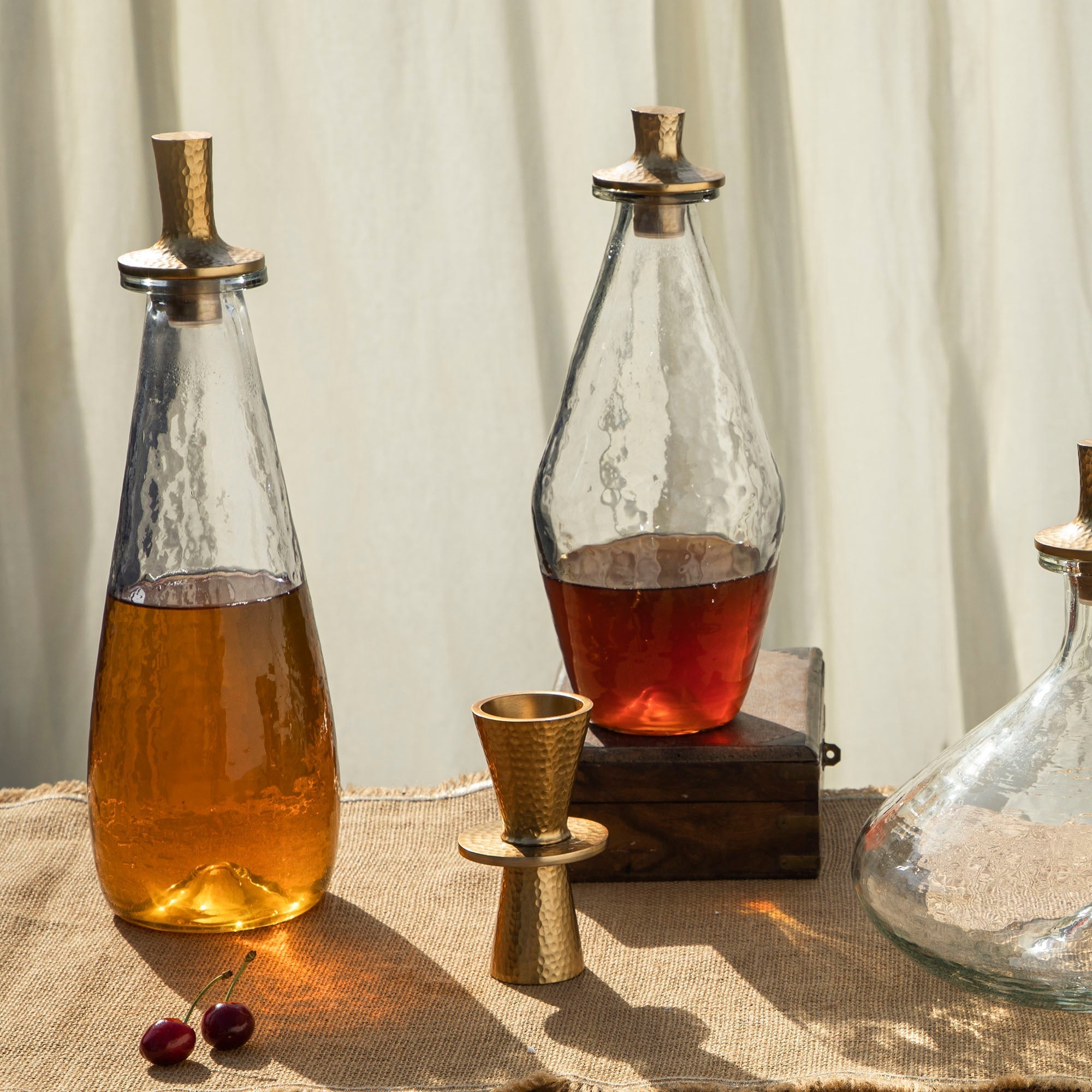 Two glass decanters with liquid on a textured surface with a neutral background
