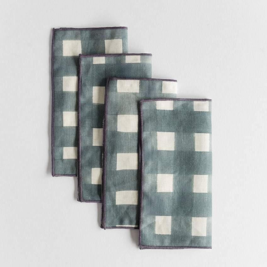Set of four blue checkered napkins on a light gray background