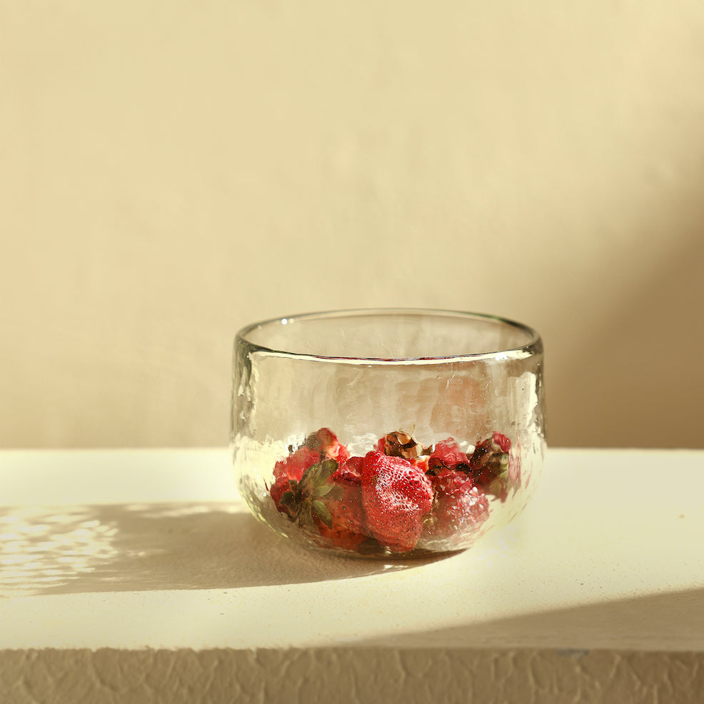 Clear pebbled glass bowl with dried flowers on a beige surface