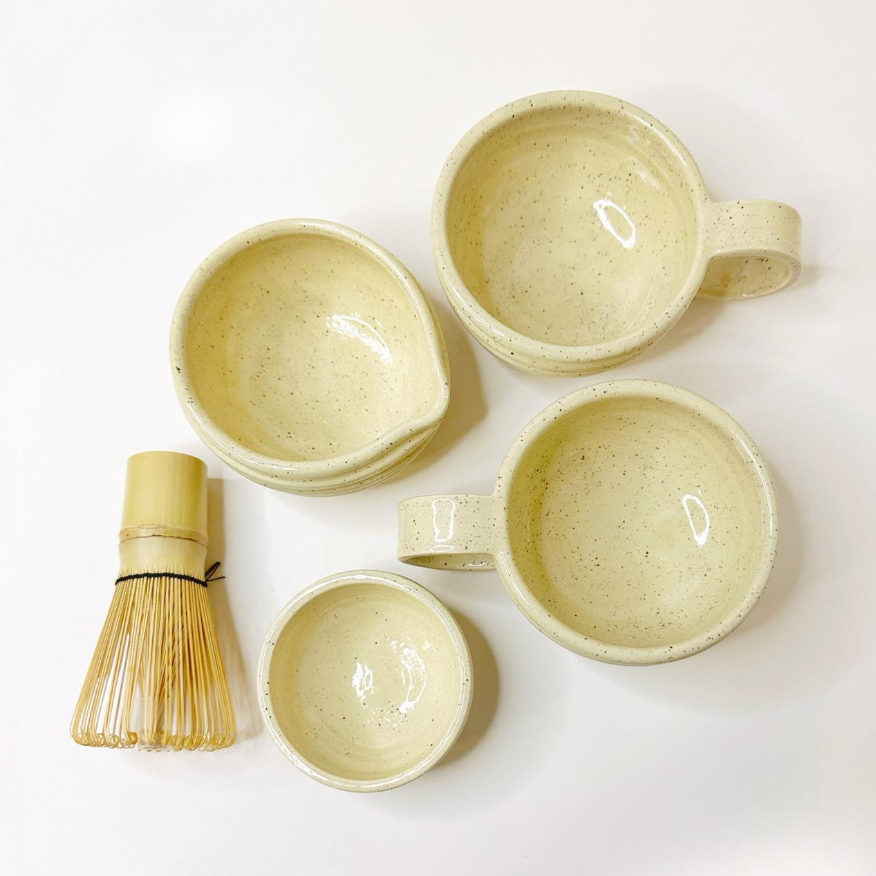 Set of ceramic bowls and a whisk on a white background