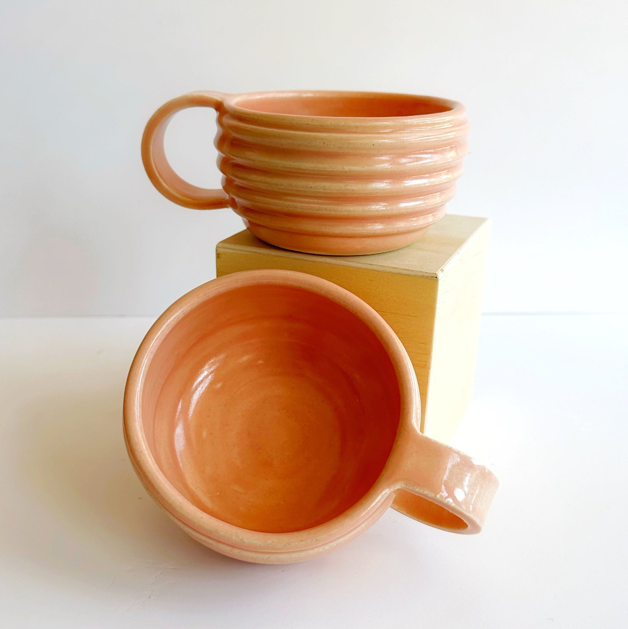 Two terracotta ceramic mugs on a white background