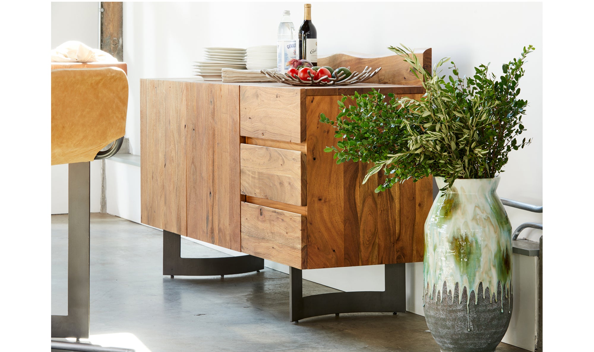 Wooden sideboard with a vase of greenery and a plant on a white background