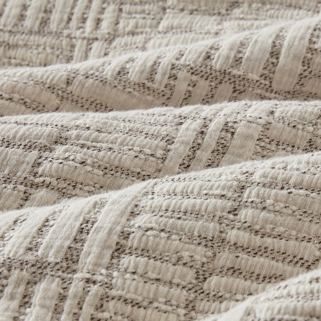 Close-up of textured beige comforter with a subtle pattern