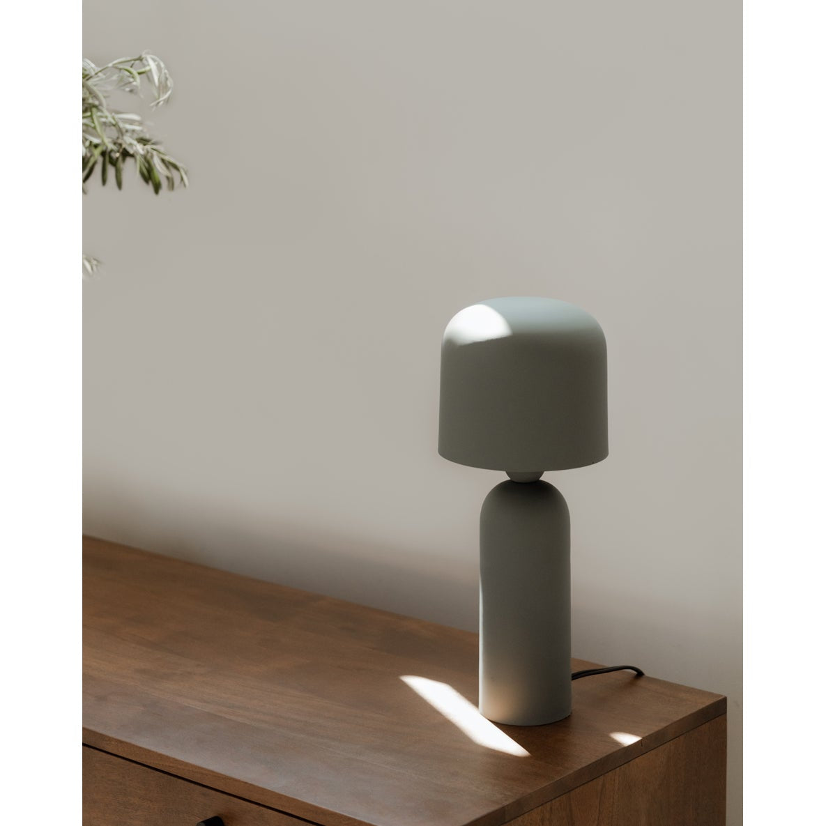 Green table lamp on a wooden surface with a neutral background