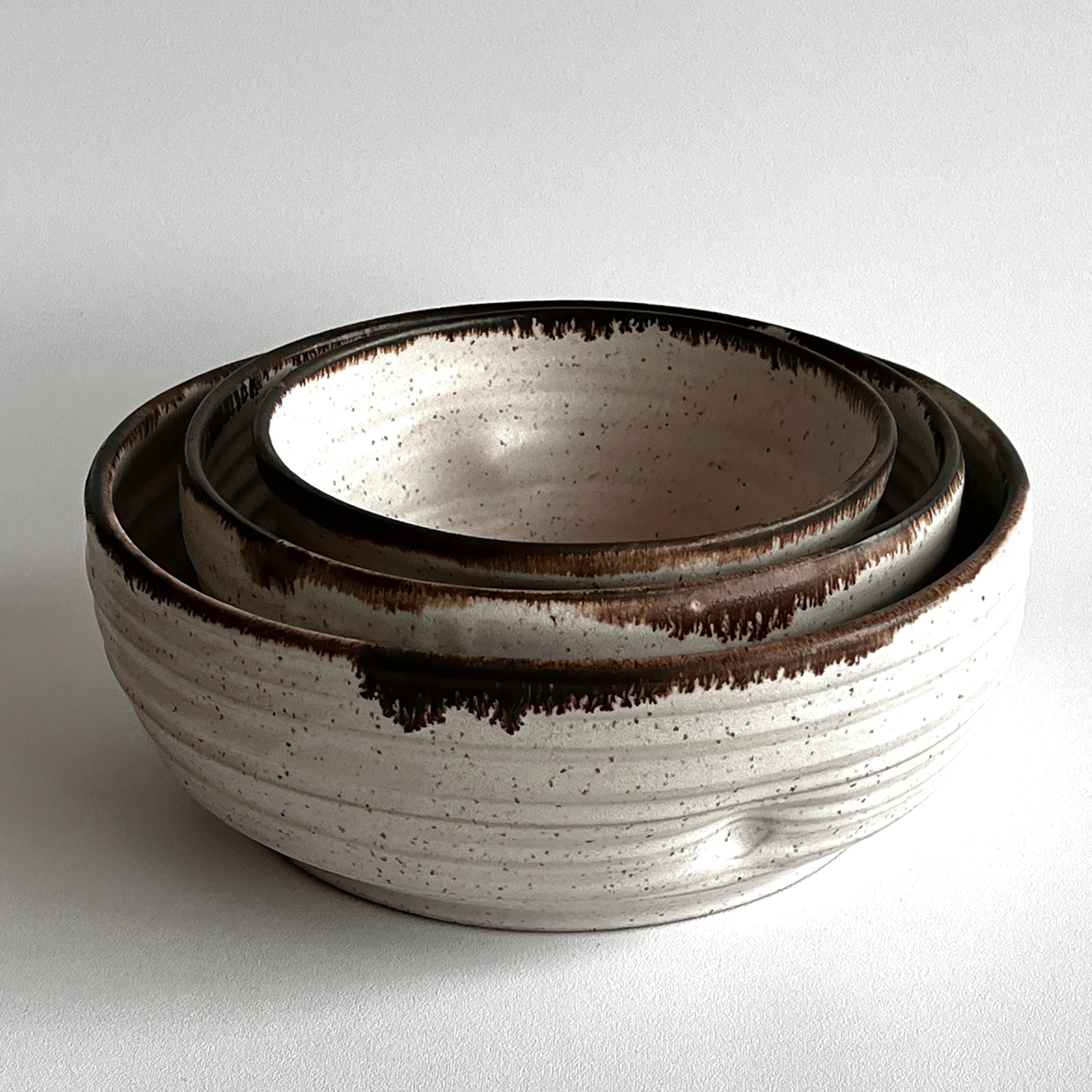 Set of three ceramic bowls with brown accents on a light gray background