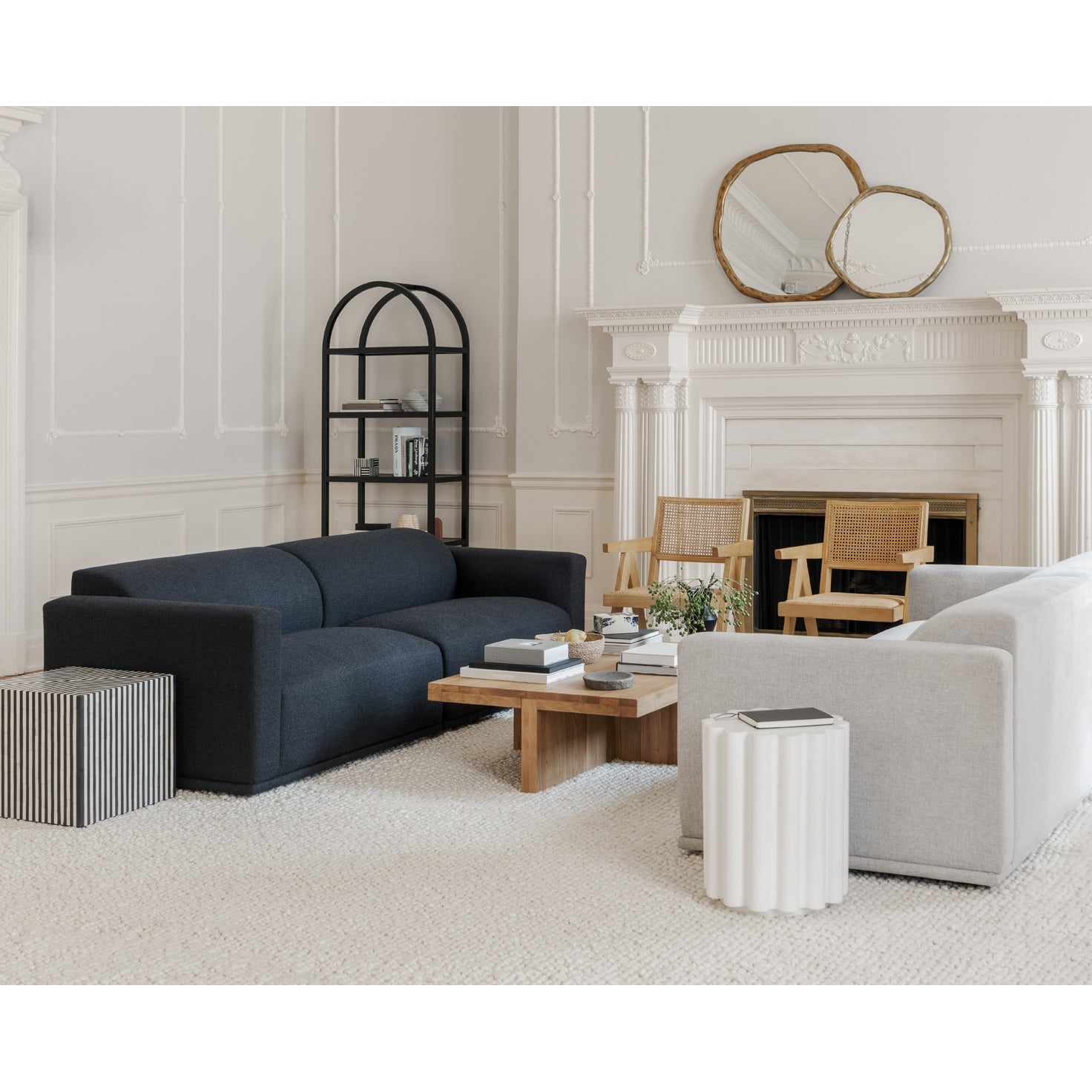 Modern living room with a black sofa, white armchair, and decorative elements.