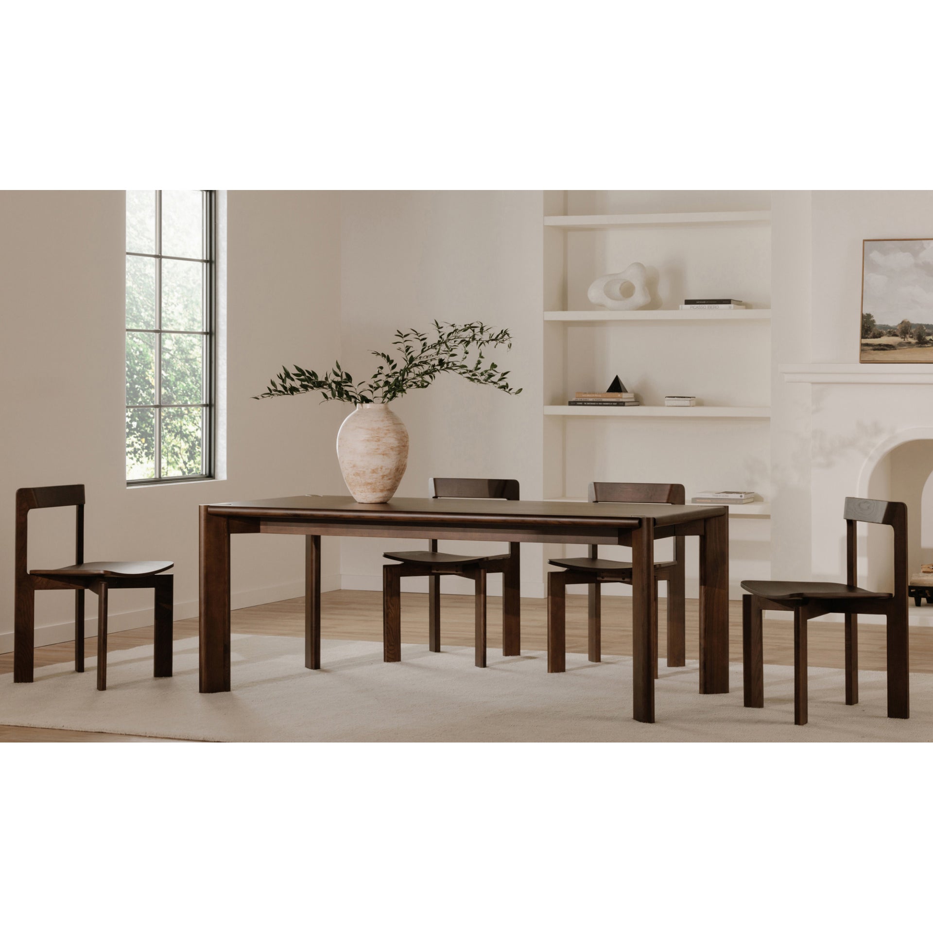 Dining room with wooden table and chairs, vase with branches on the table.