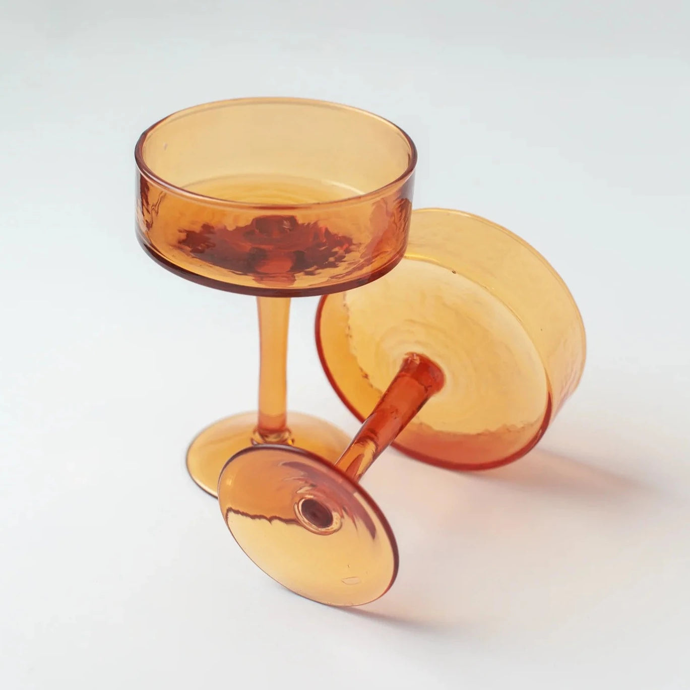 Amber-colored cocktail glasses on a light gray background