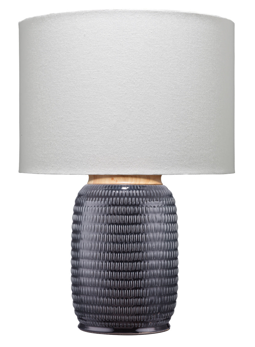 Table lamp with ribbed dark navy ceramic base and white shade on a white background