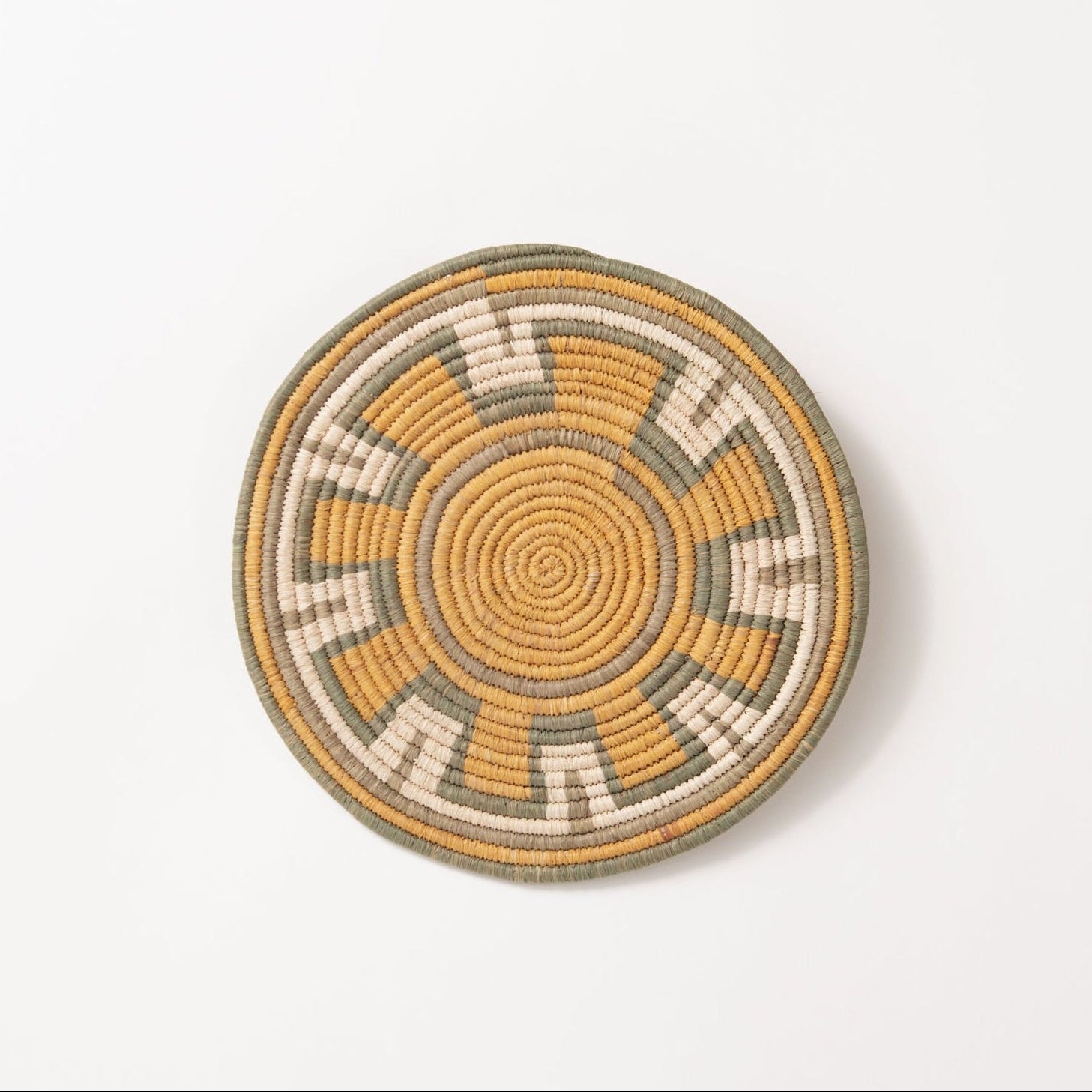 Round woven coaster trivet with concentric circle pattern on a white background