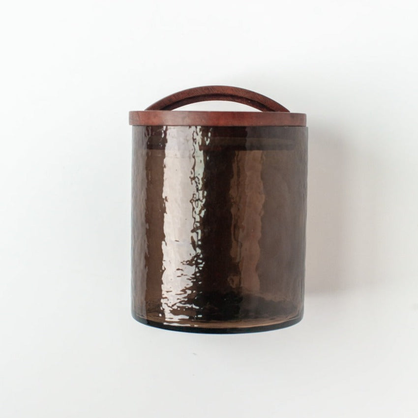 Brown hammered glass canister with wooden handle on a white background