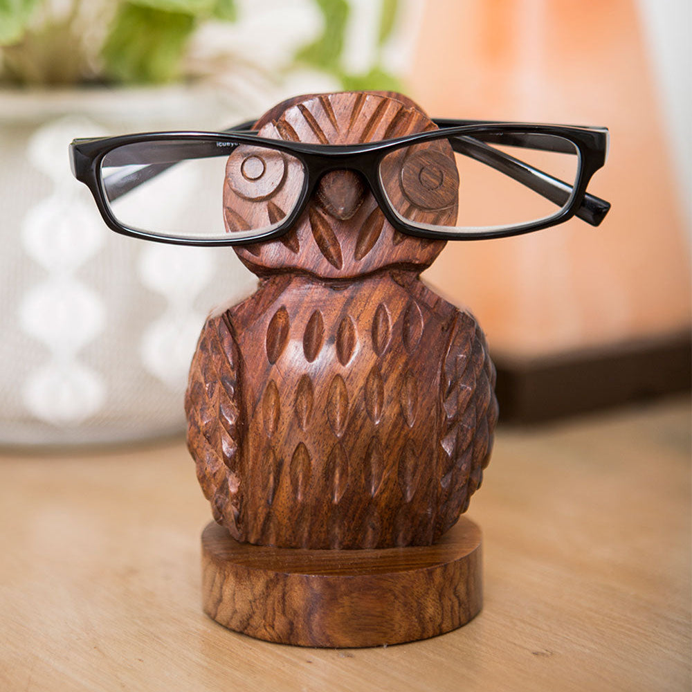 Wooden owl-shaped eyeglass holder with glasses on a wooden surface
