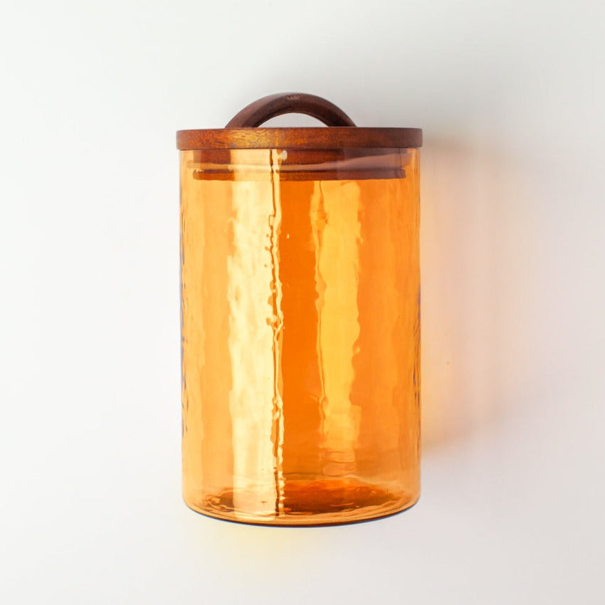 Amber glass jar with wooden lid on a white background