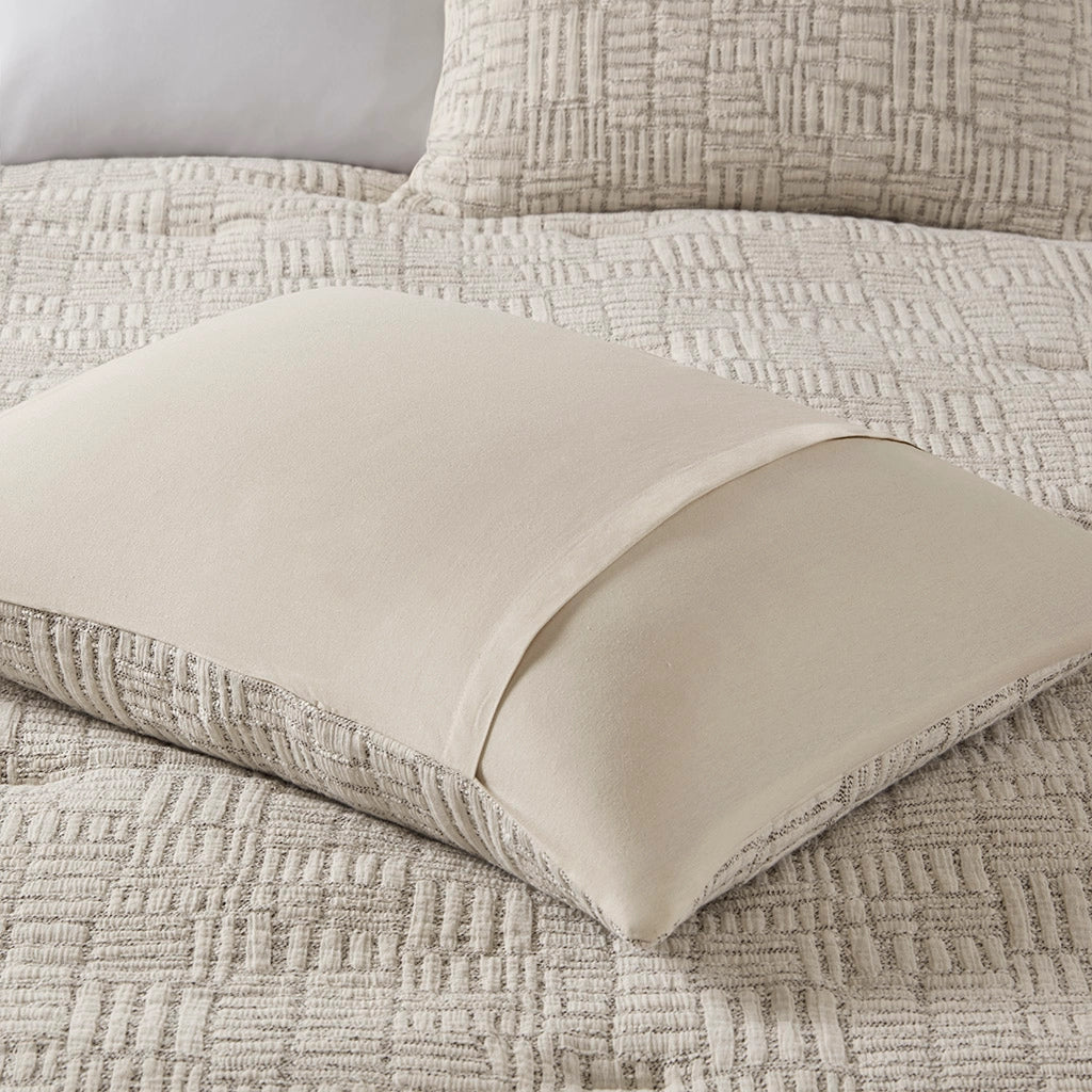 Textured beige pillow on a matching textured blanket