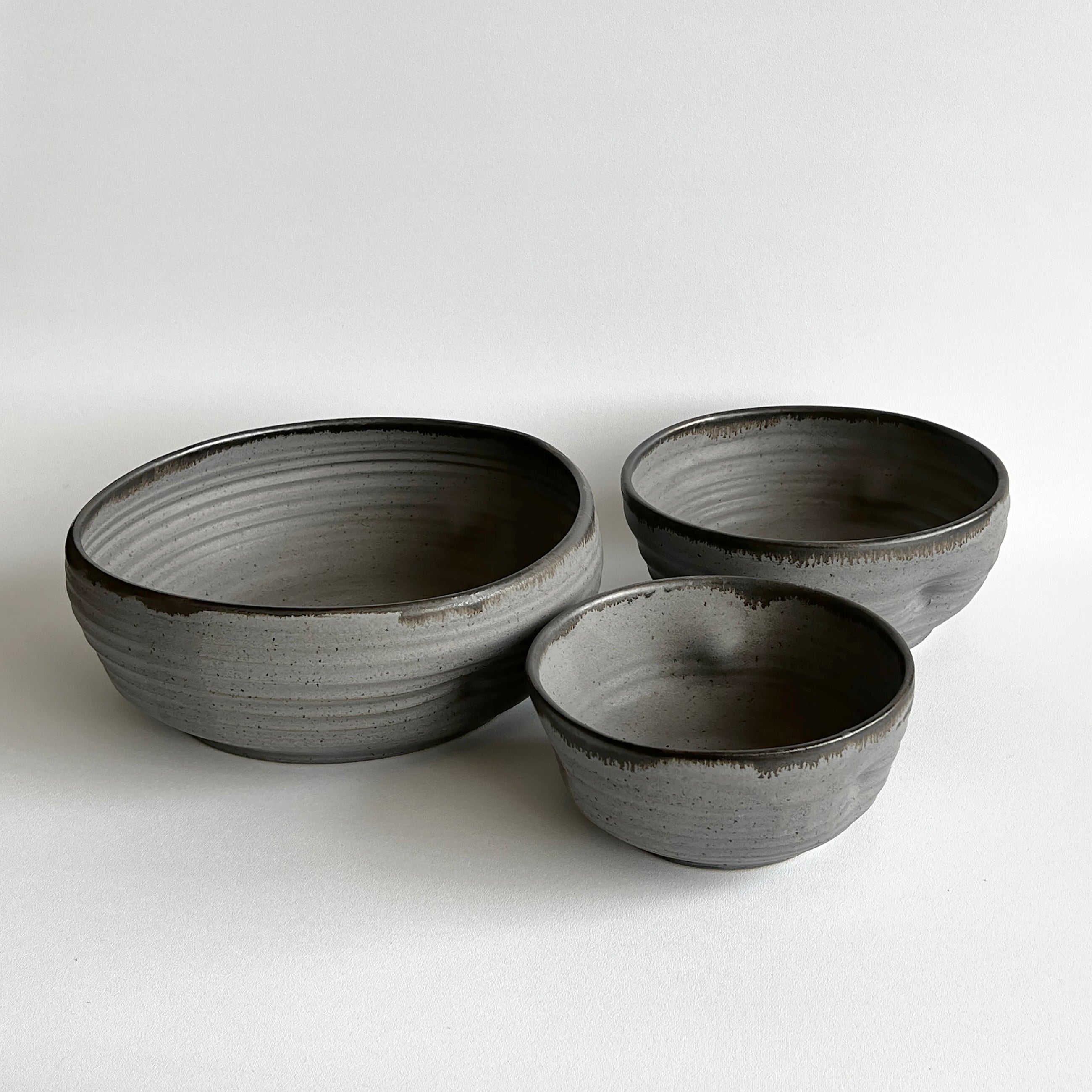 Three gray ceramic bowls of varying sizes on a white background