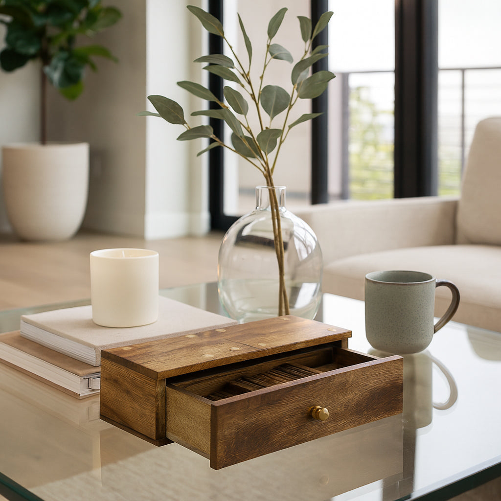 Wooden box with a drawer on a glass coffee table in a living room setting.