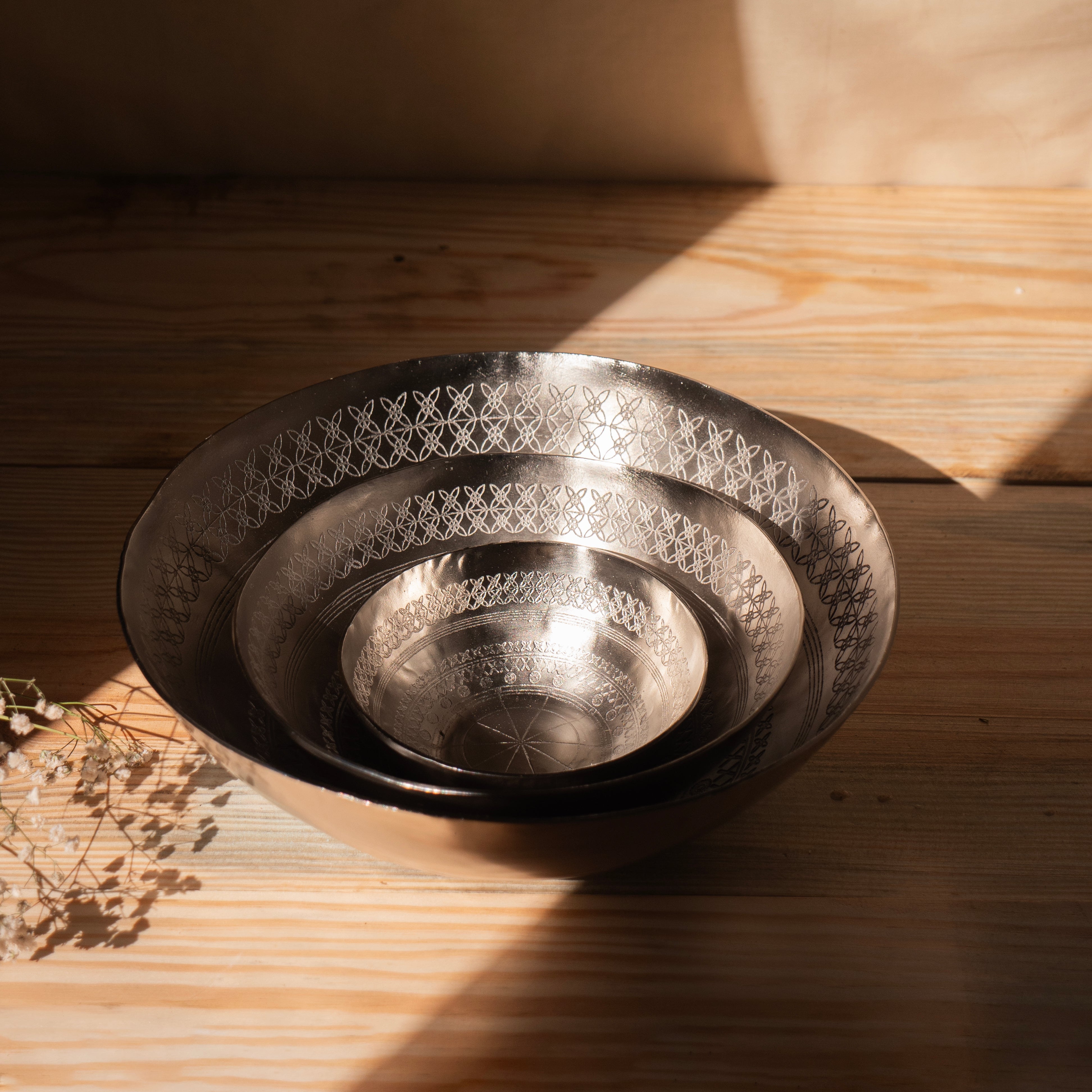 Set of metallic bowls on a wooden surface with warm lighting