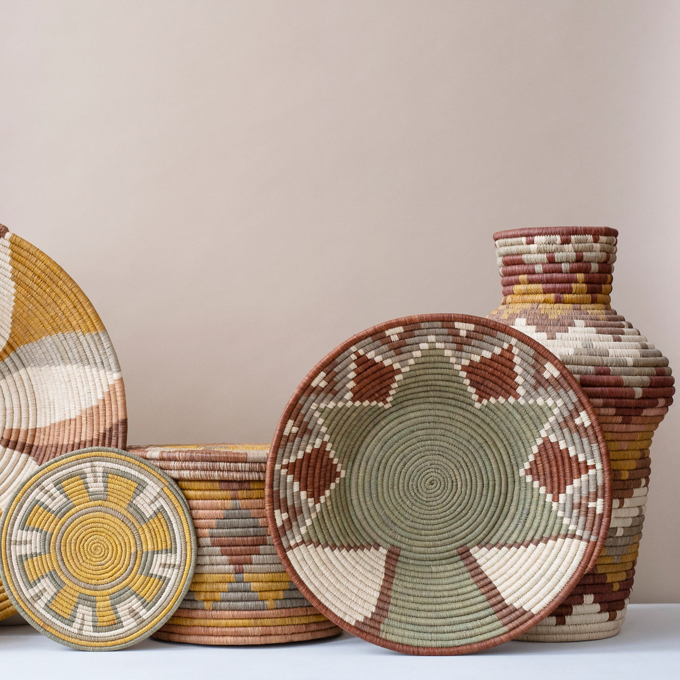 Set of sustainably sourced woven baskets and a vase on a neutral background