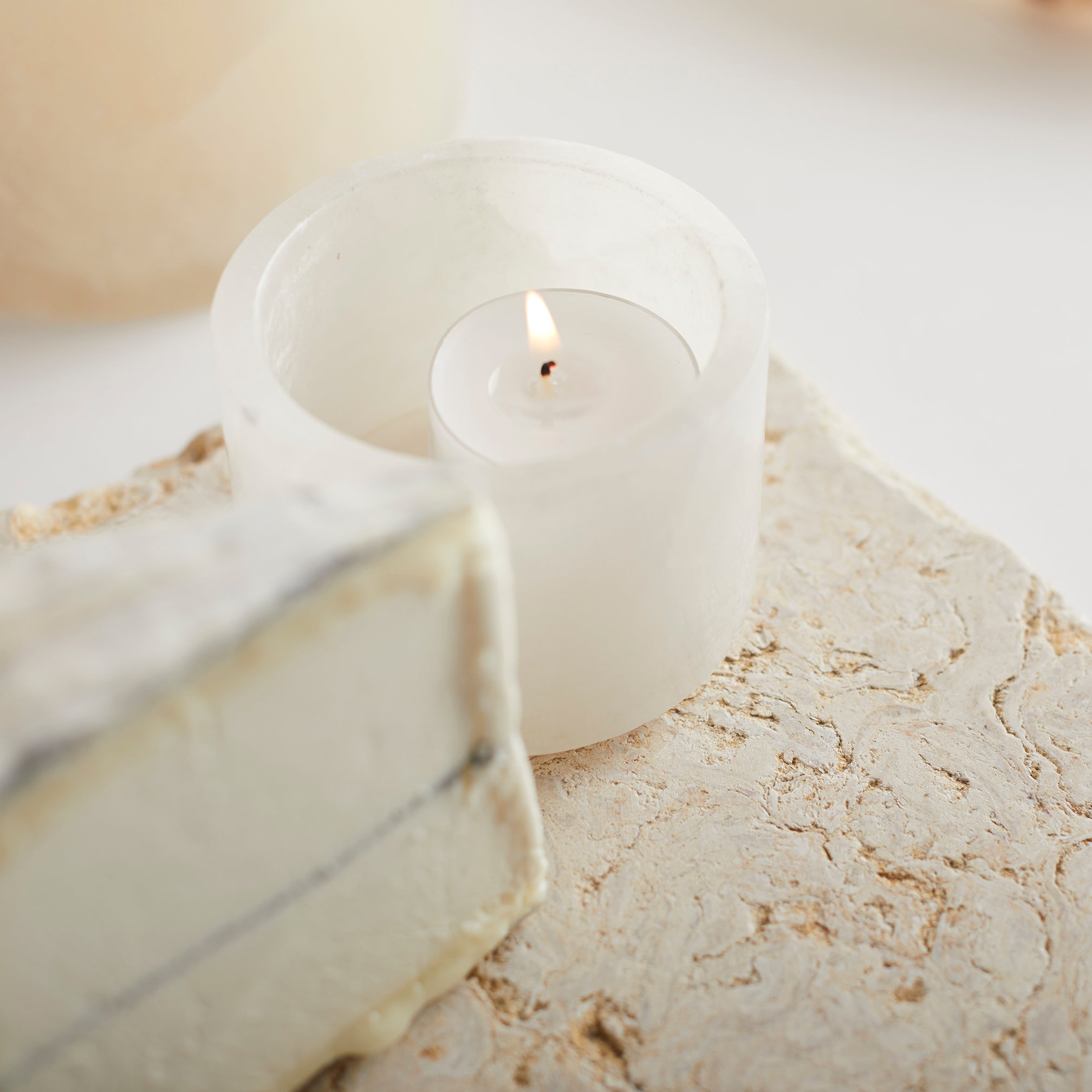 White candle in a stone holder on a marble surface