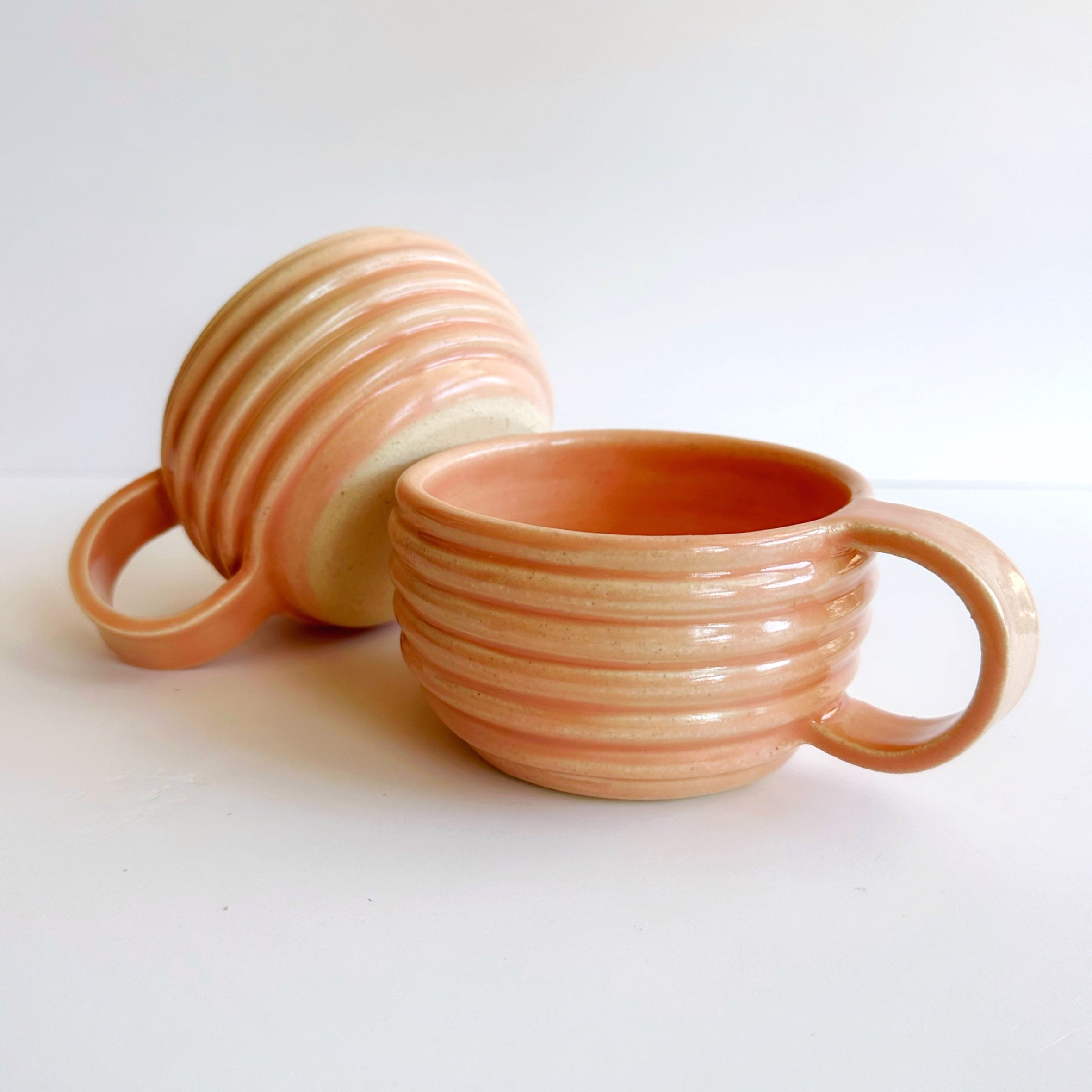 Two ceramic mugs with ribbed texture on a white background
