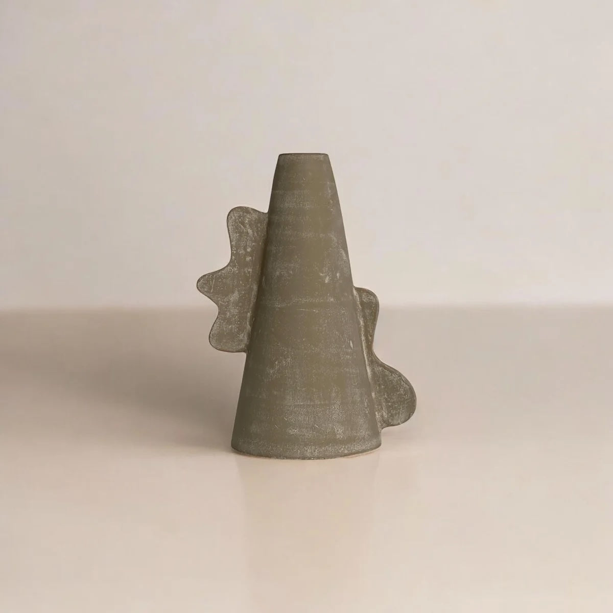 Cylindrical vessel with leaf-like extensions on a beige background