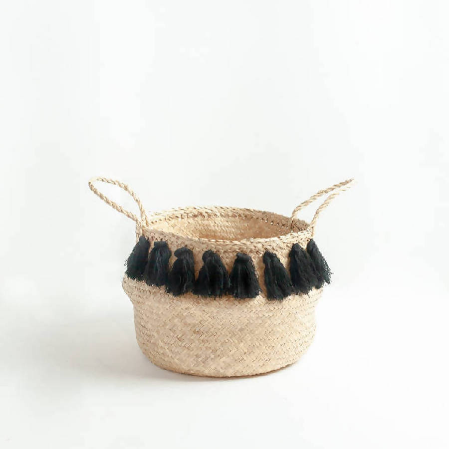 Woven basket with black tassels on a white background