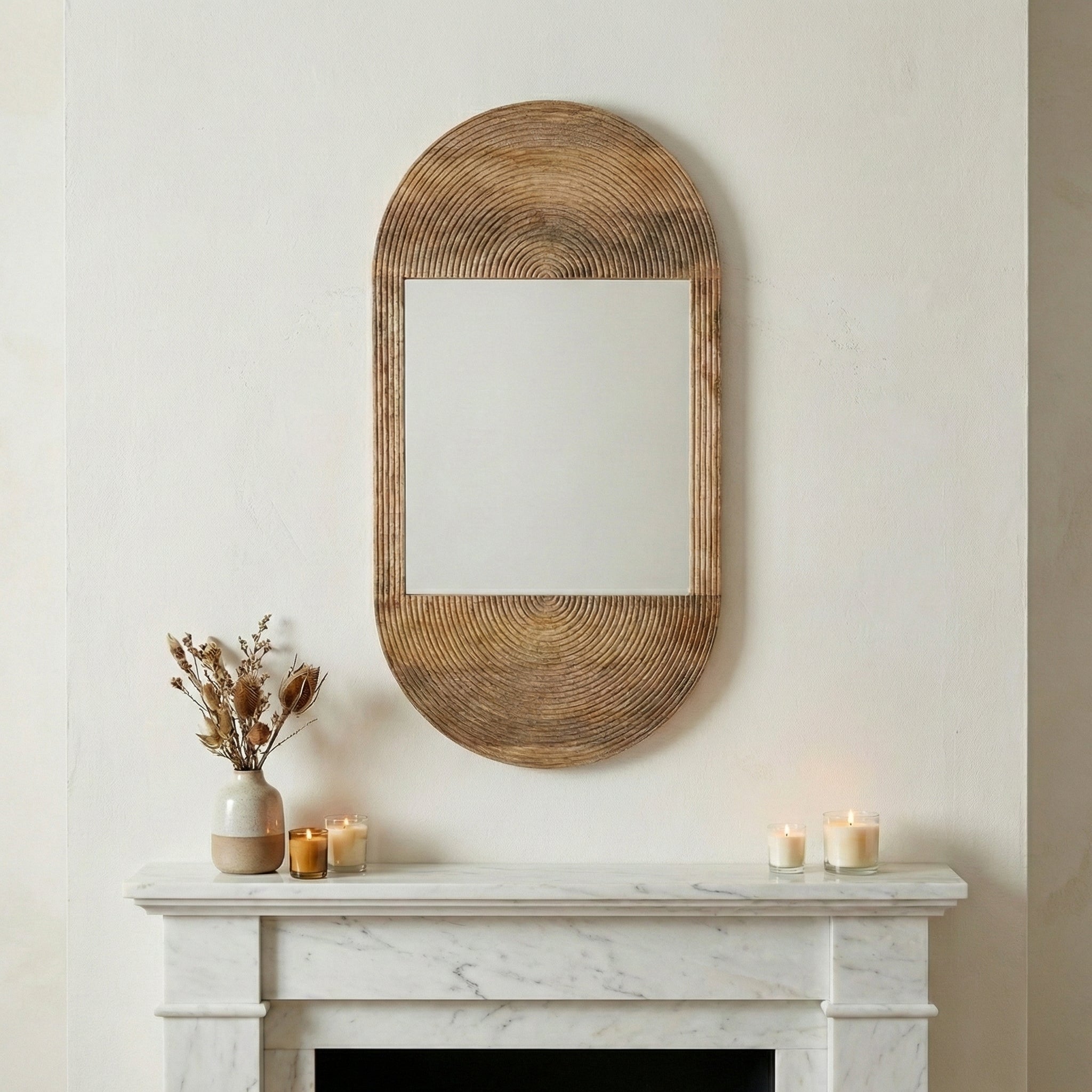 Woven mirror on a wall above a fireplace with candles and decor.