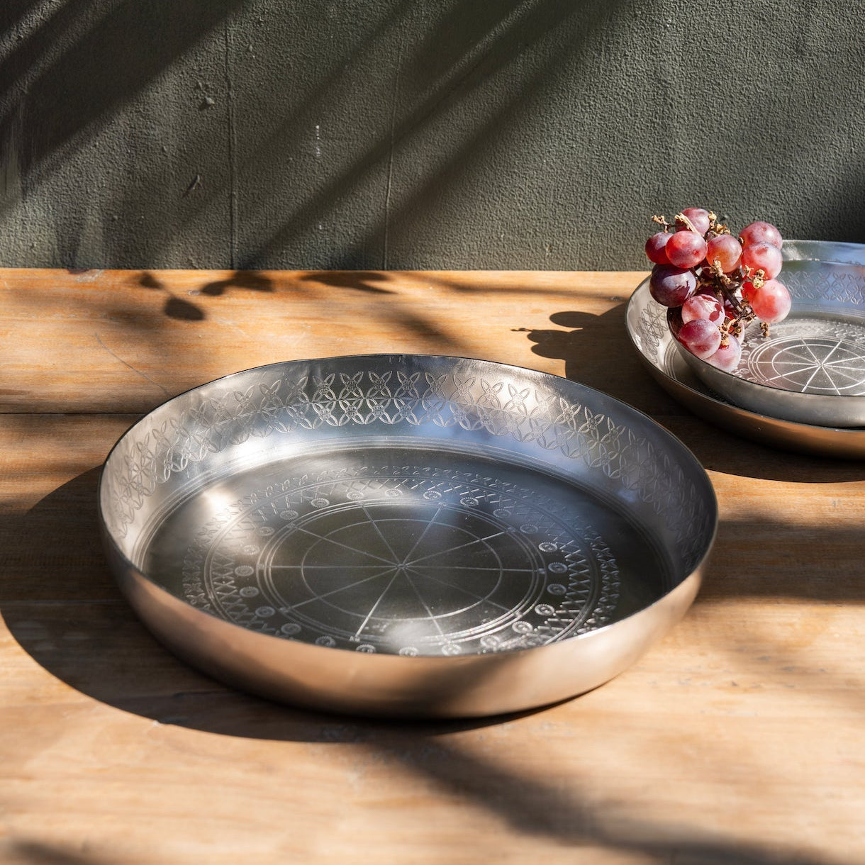 Decorative metal trays on a wooden surface with a dark wall background