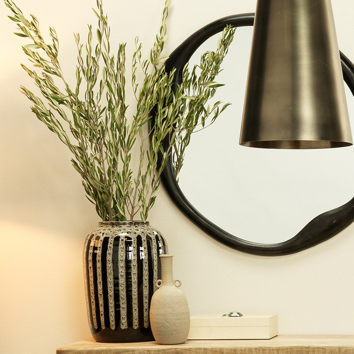 Decorative vases with plants on a shelf against a wall with a mirror.