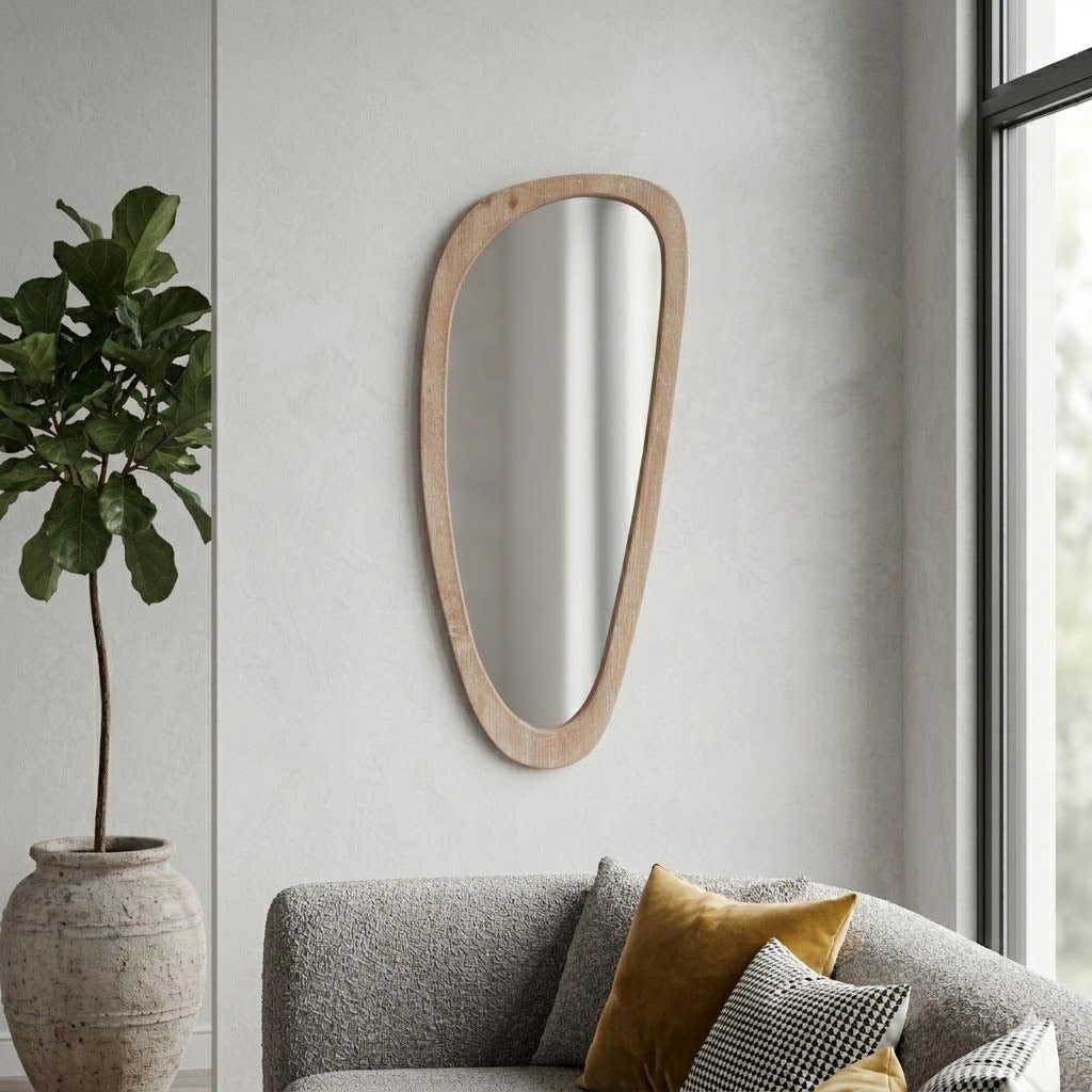 Wooden mirror on a wall above a sofa with decorative pillows and a plant.