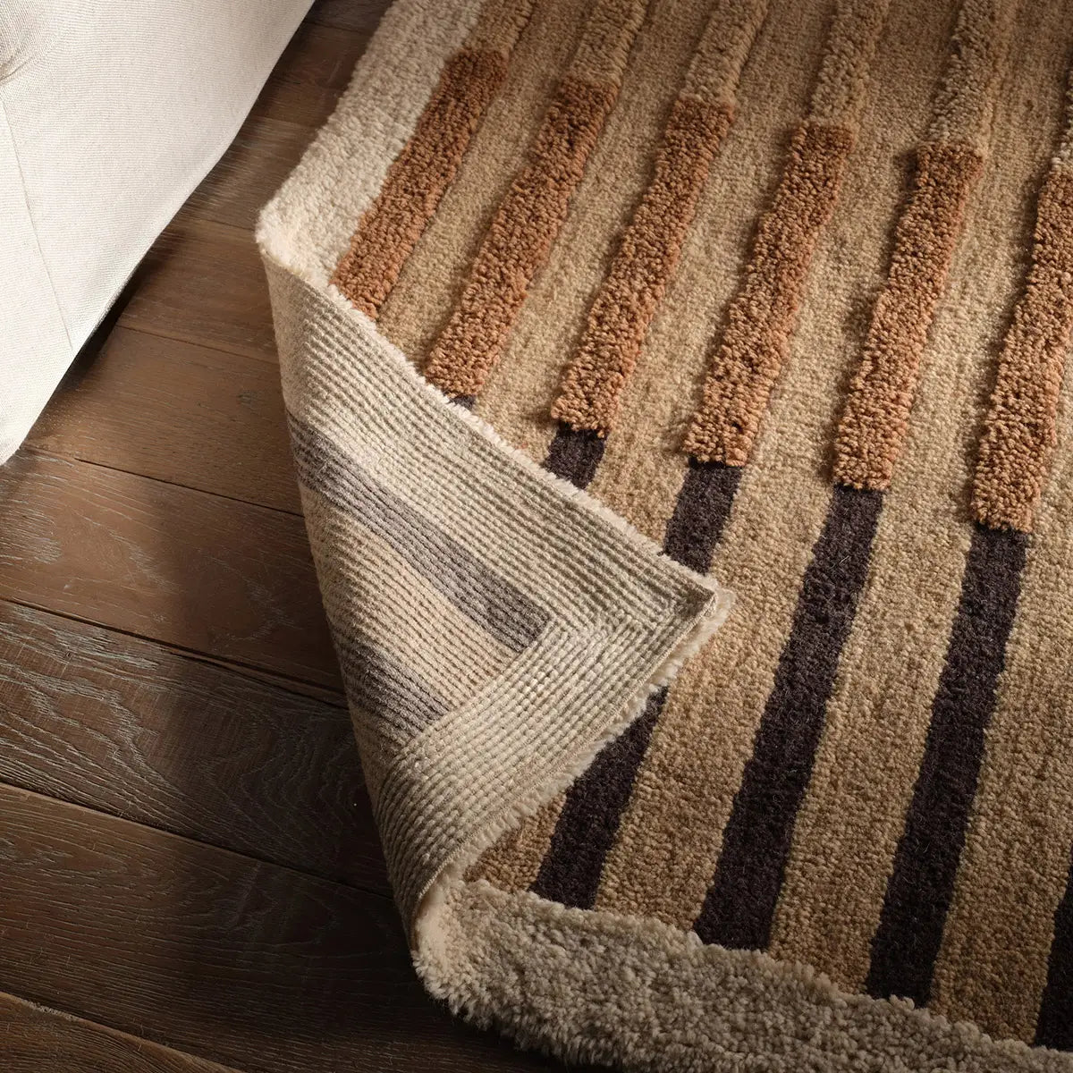 Close-up of a textured rug with brown and beige pattern on a wooden floor.
