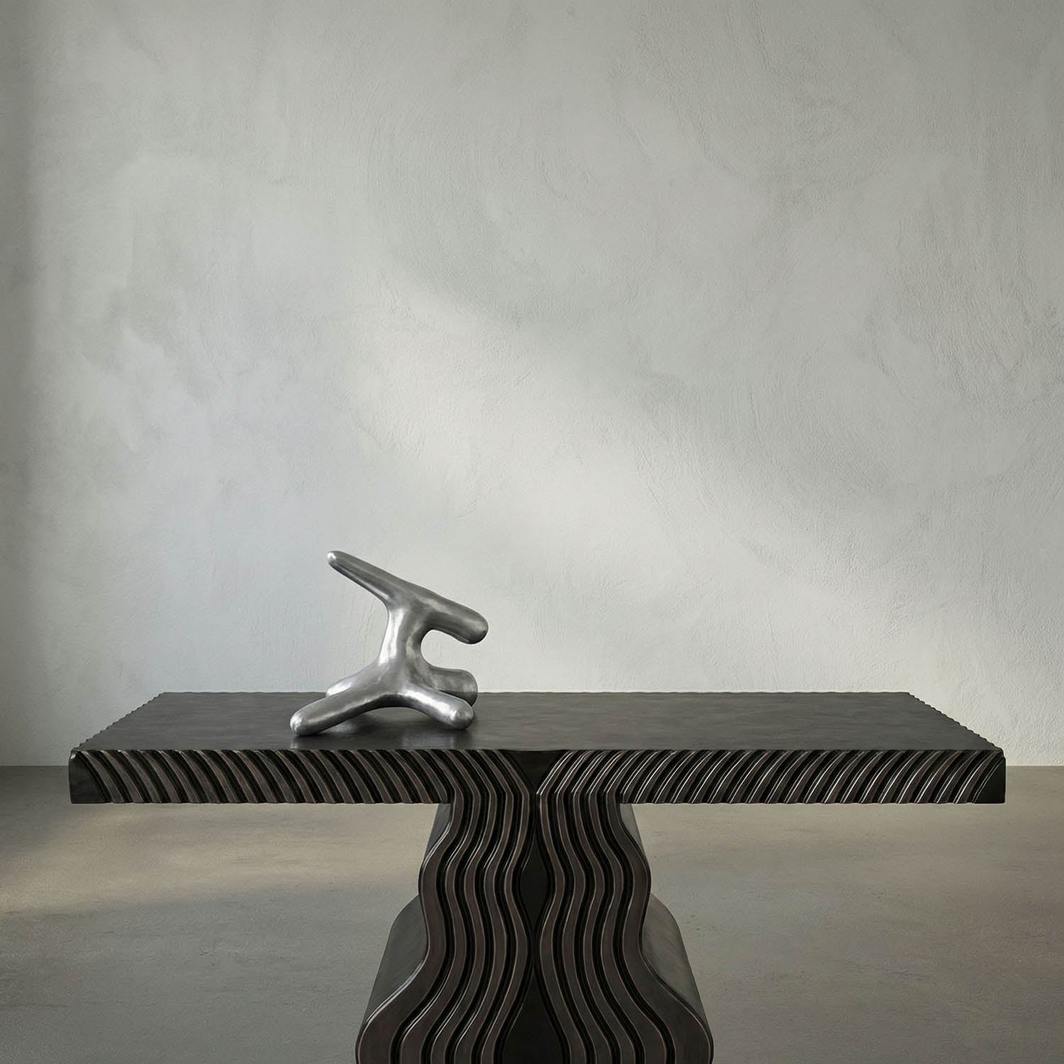 Abstract sculpture on a textured black platform against a gray wall
