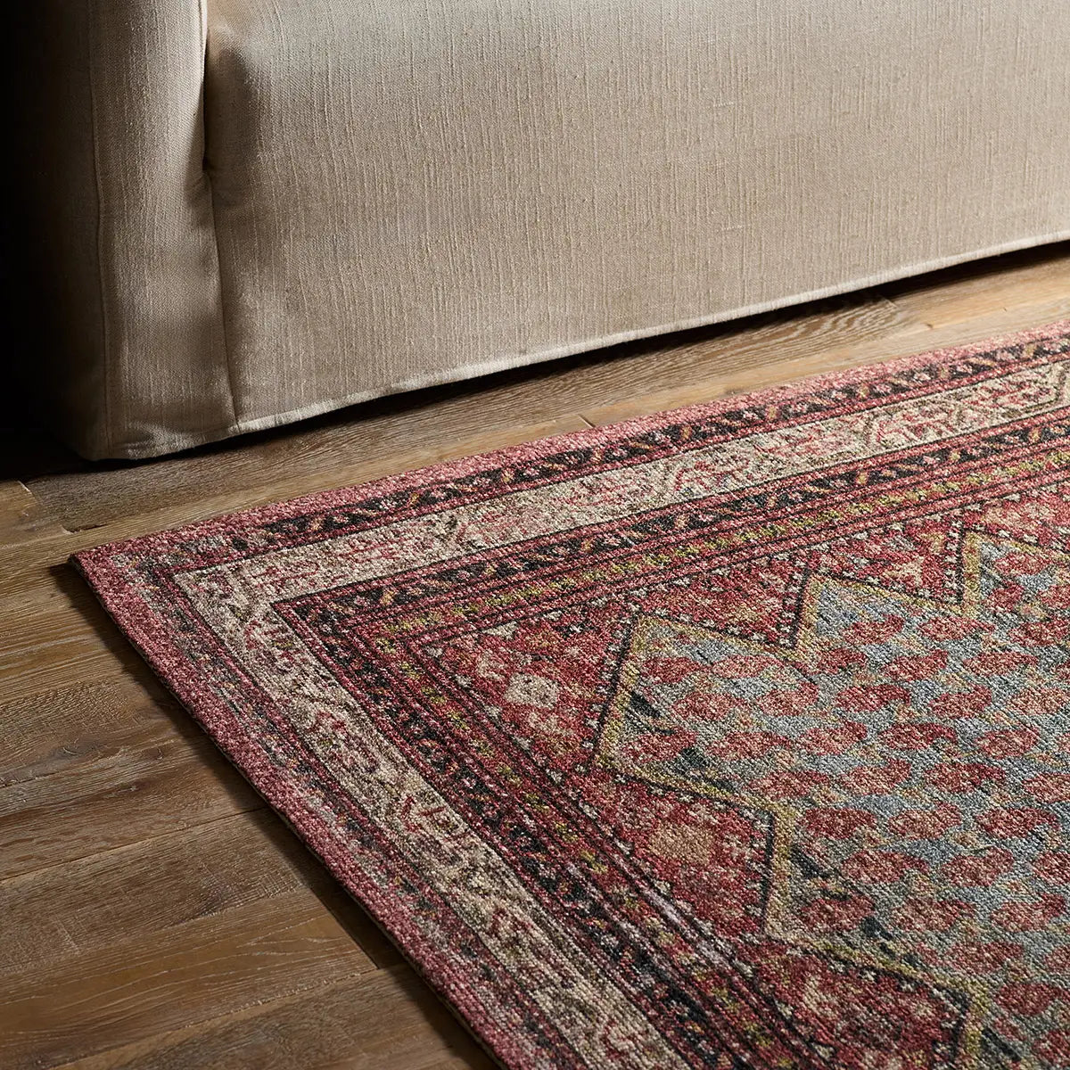 Patterned rug on a wooden floor next to a beige sofa