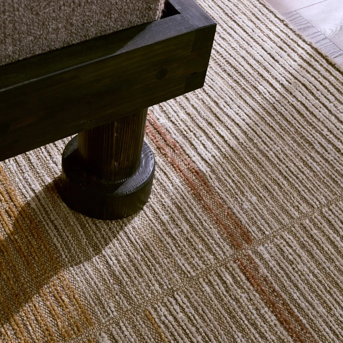 Close-up of a textured carpet with a wooden chair leg.