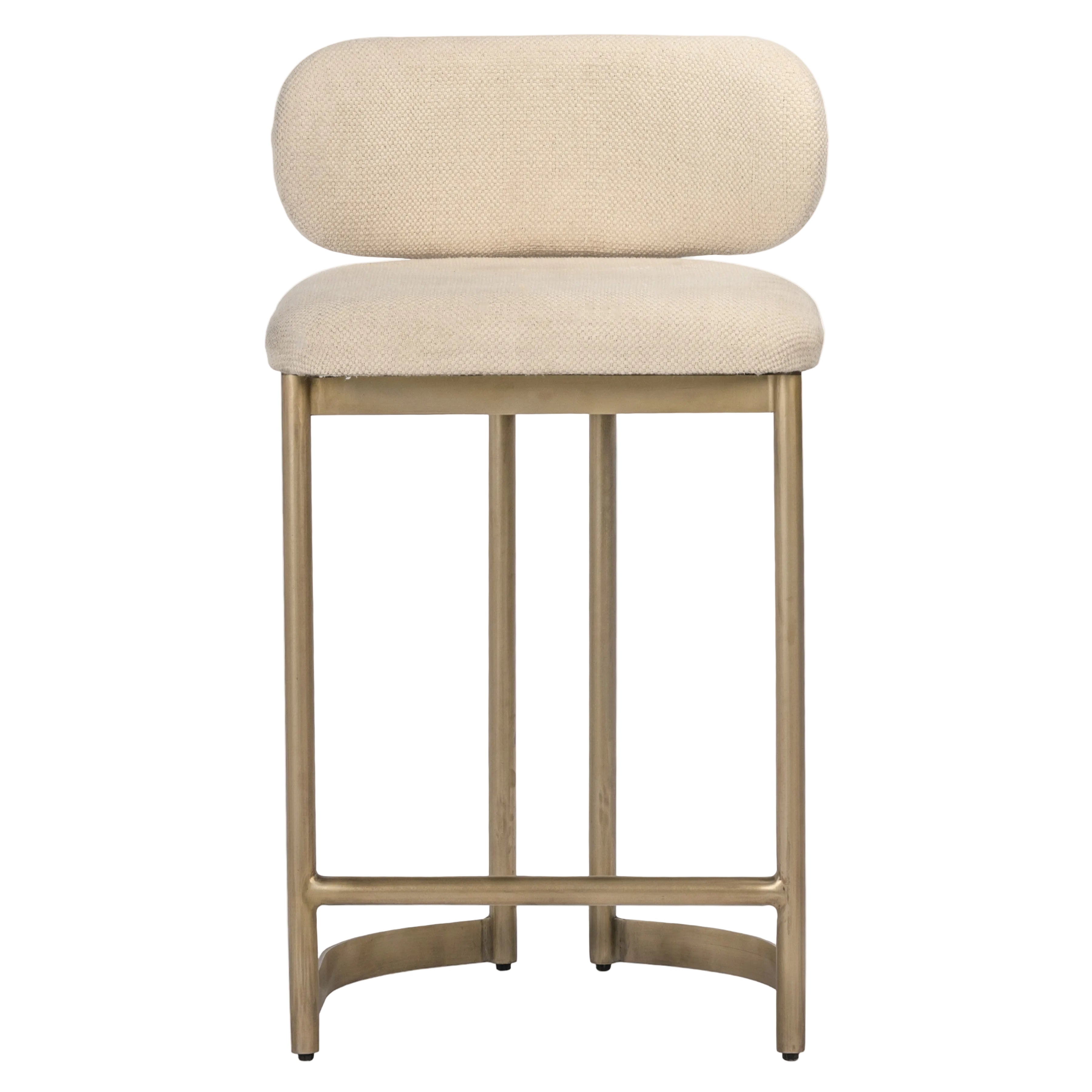 A modern barstool with a rounded, low-profile upholstered backrest and seat cushion in a textured cream fabric, supported by a slim, brushed gold metal frame.