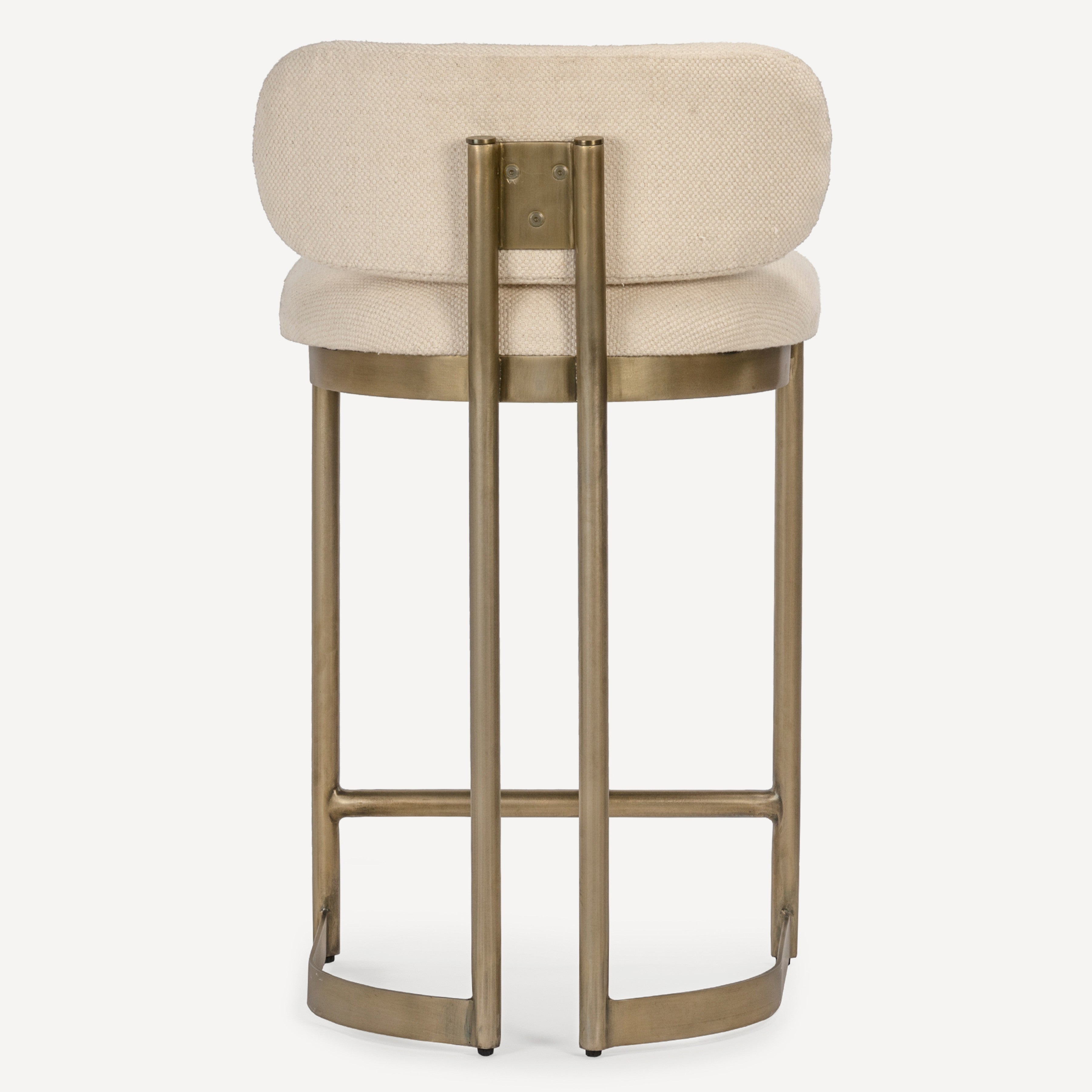 A modern bar stool with a round, low-profile upholstered seat in a textured cream fabric, supported by a curved metal frame in a brushed brass finish, shown against a plain white background.