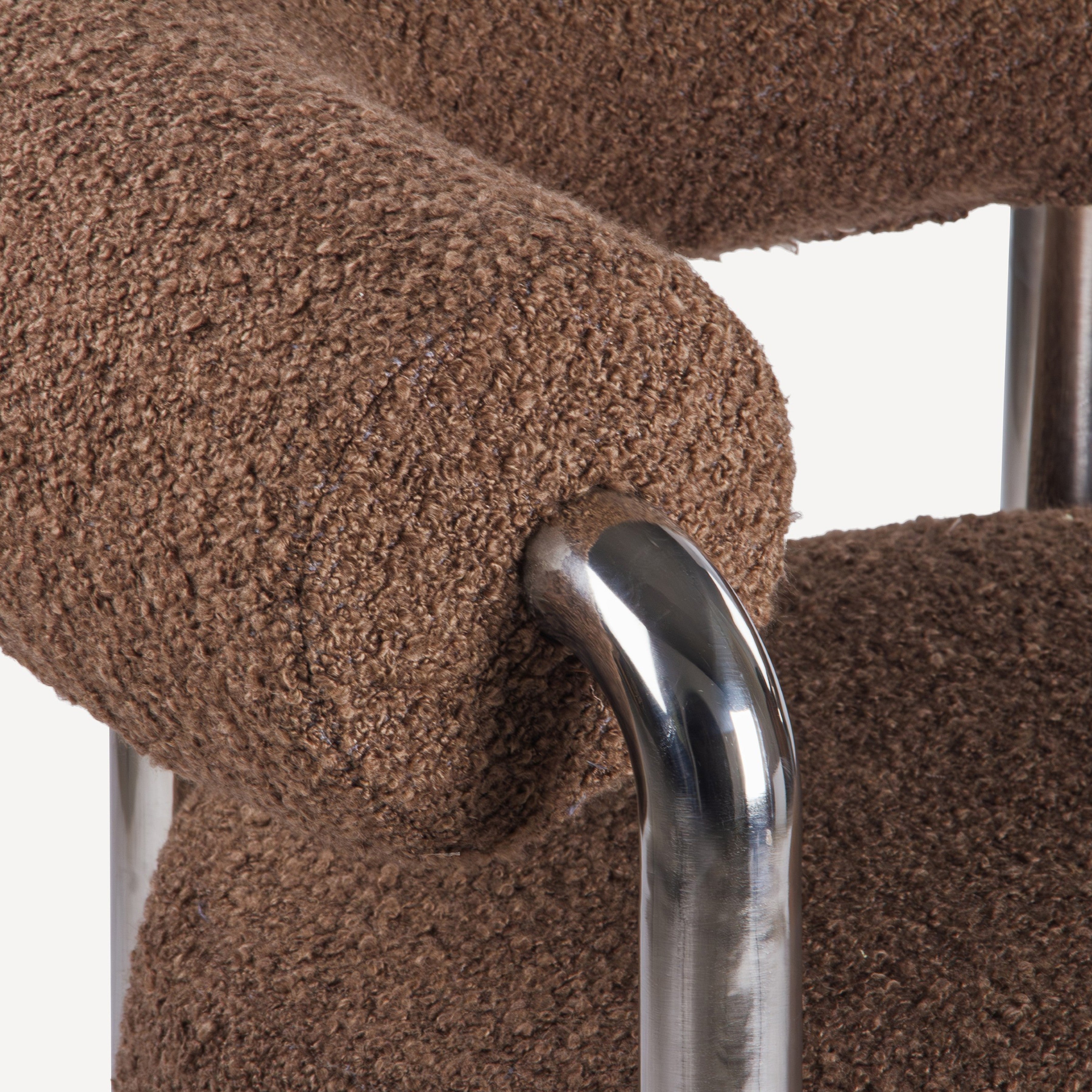 Close-up of a brown textured chair armrest with a metallic armrest.