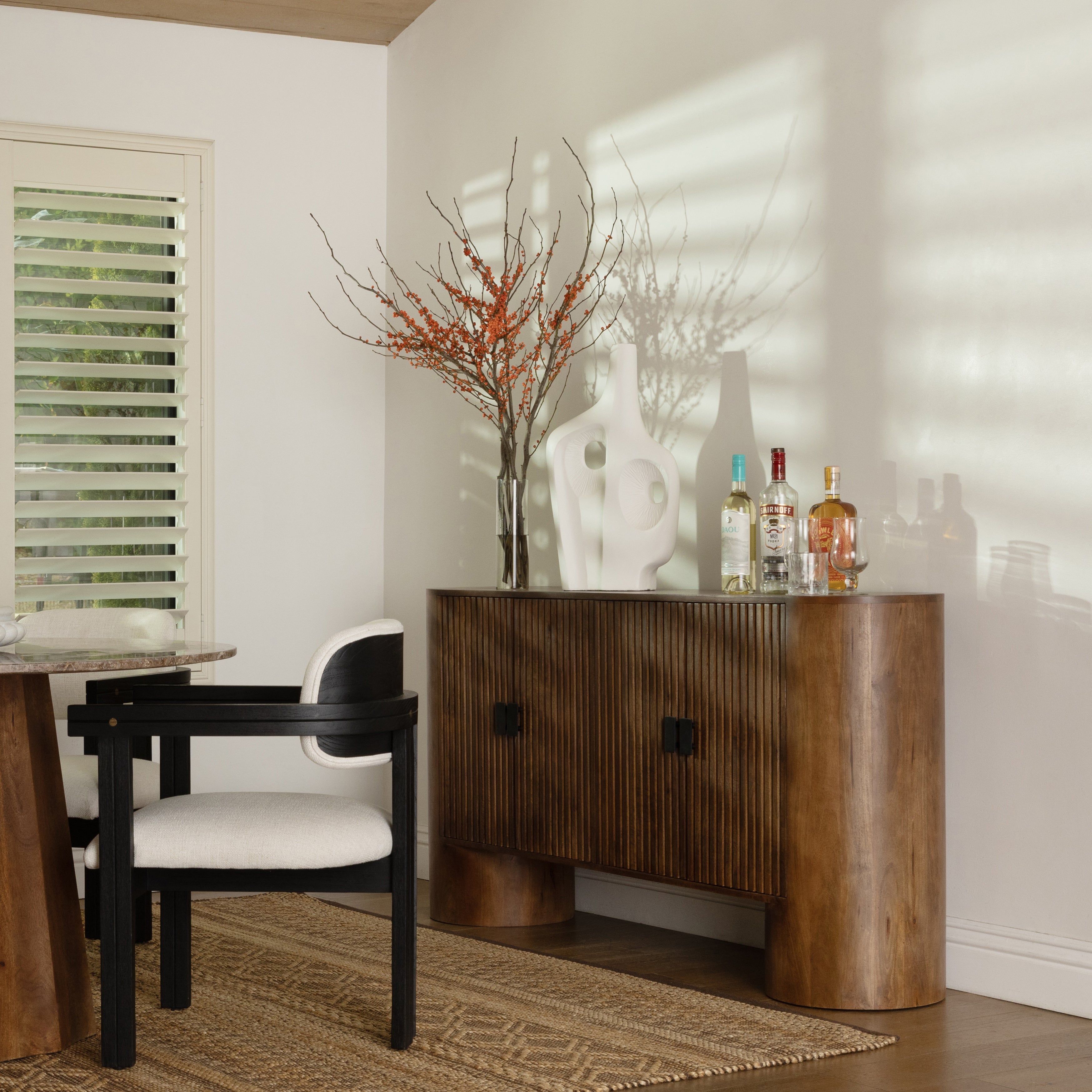 Wooden console table with decorative items in a room with a chair and window.