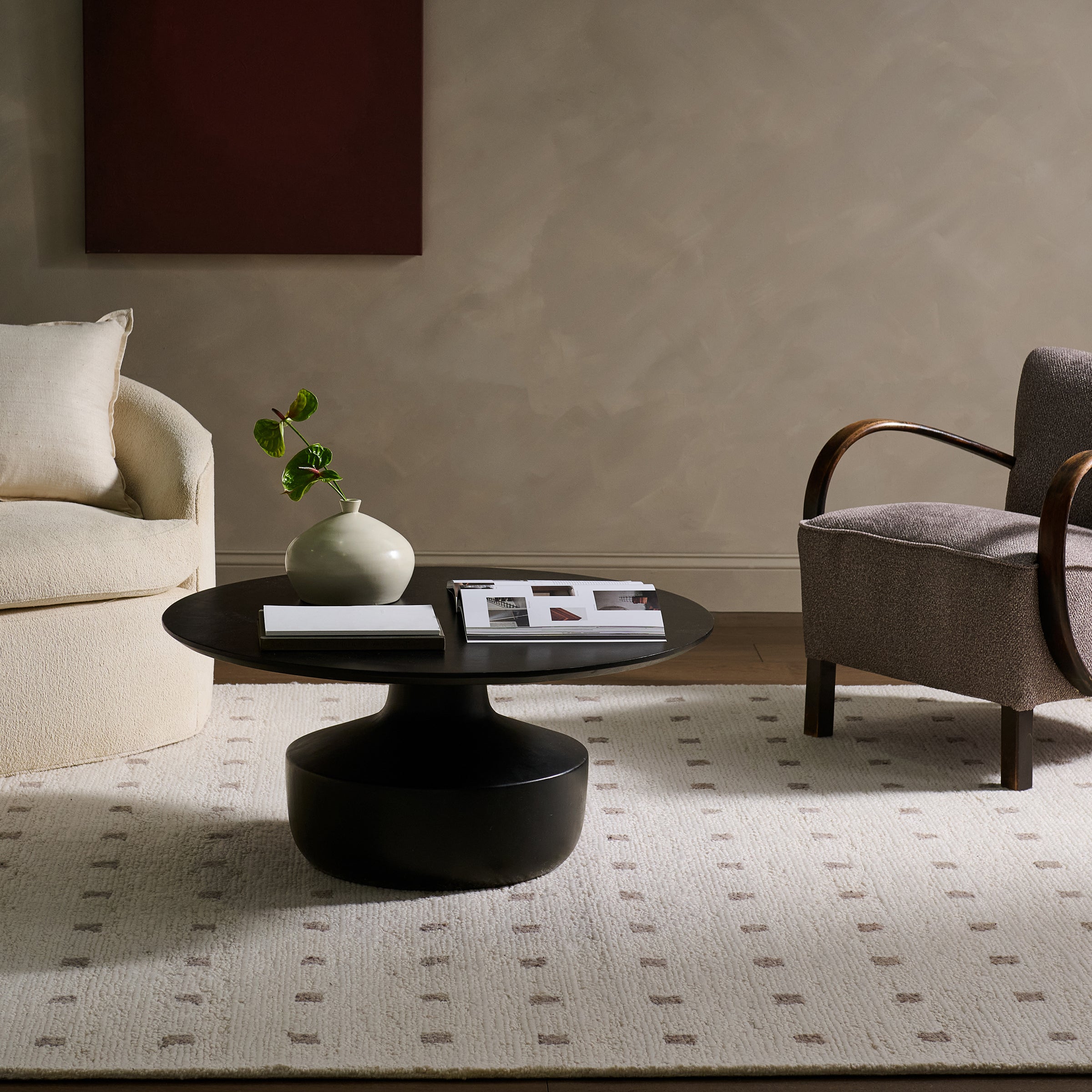 Modern living room with a black coffee table, gray armchair, and beige sofa.
