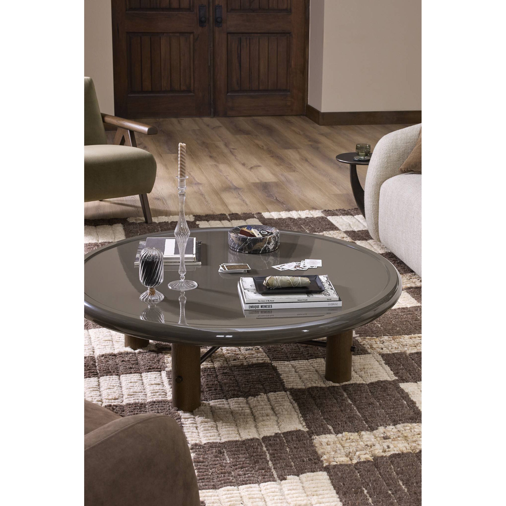 Round glass coffee table in a living room setting with decor items on top.