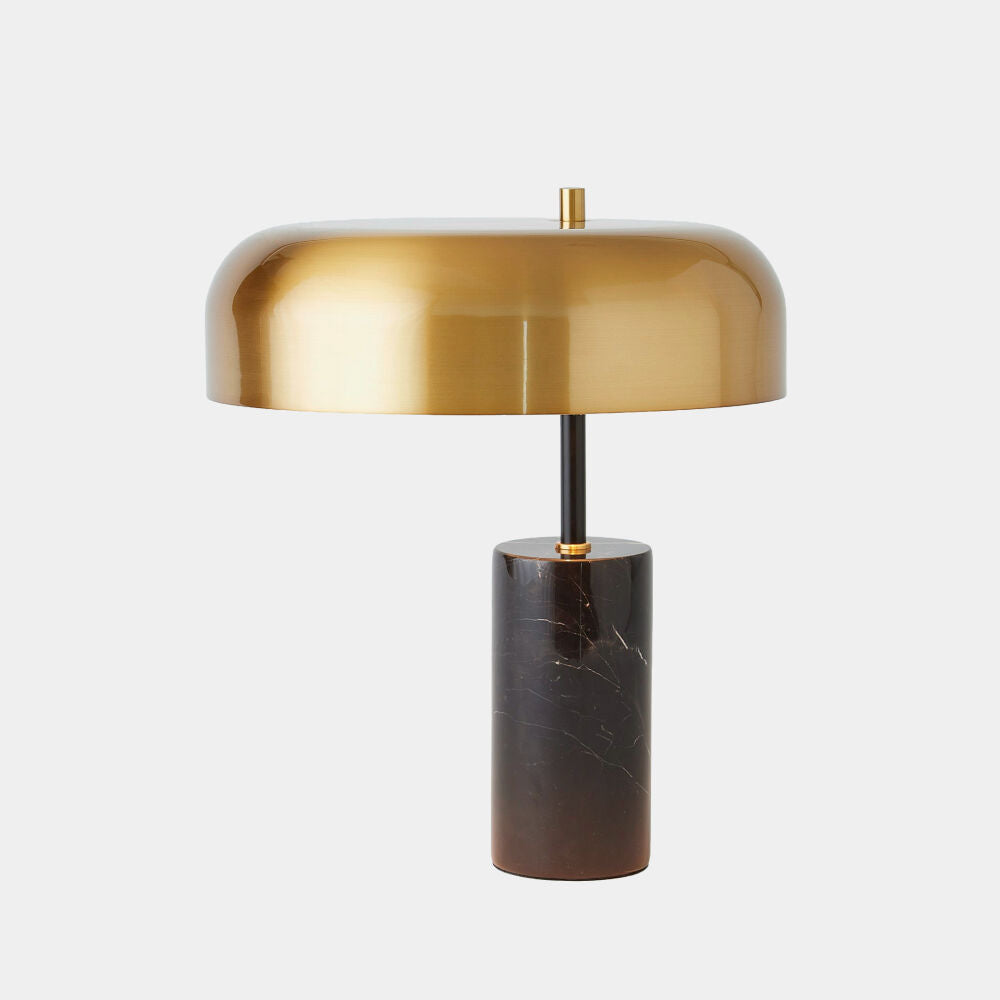 Table lamp with gold shade and black cylindrical base on a white background