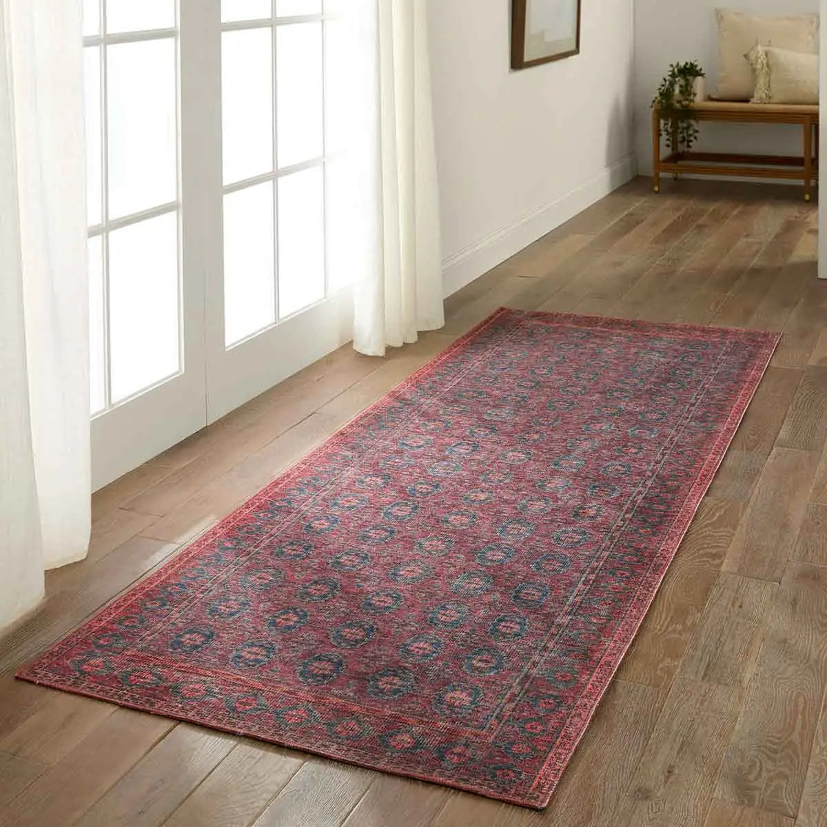 Long, patterned red rug on a wooden floor in a bright room with large windows.
