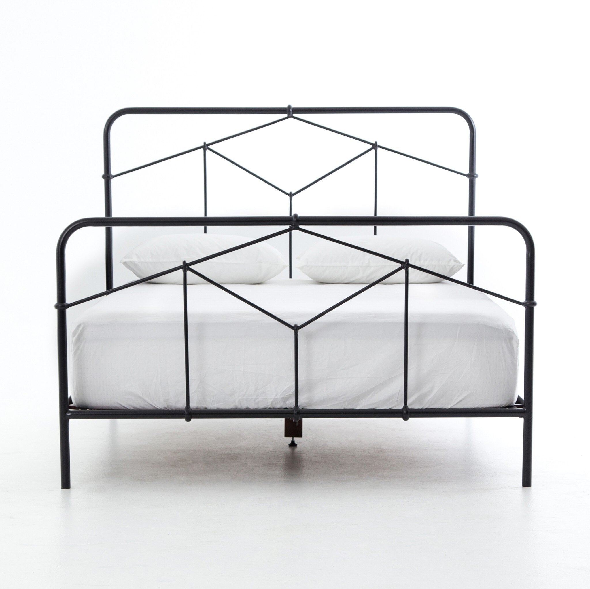 Black metal bed frame with white bedding on a white background