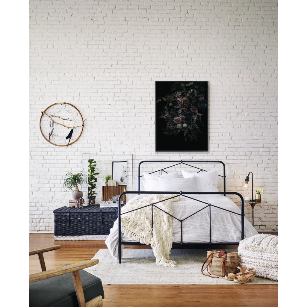 Modern bedroom with a black metal bed, white brick wall, and decorative items.