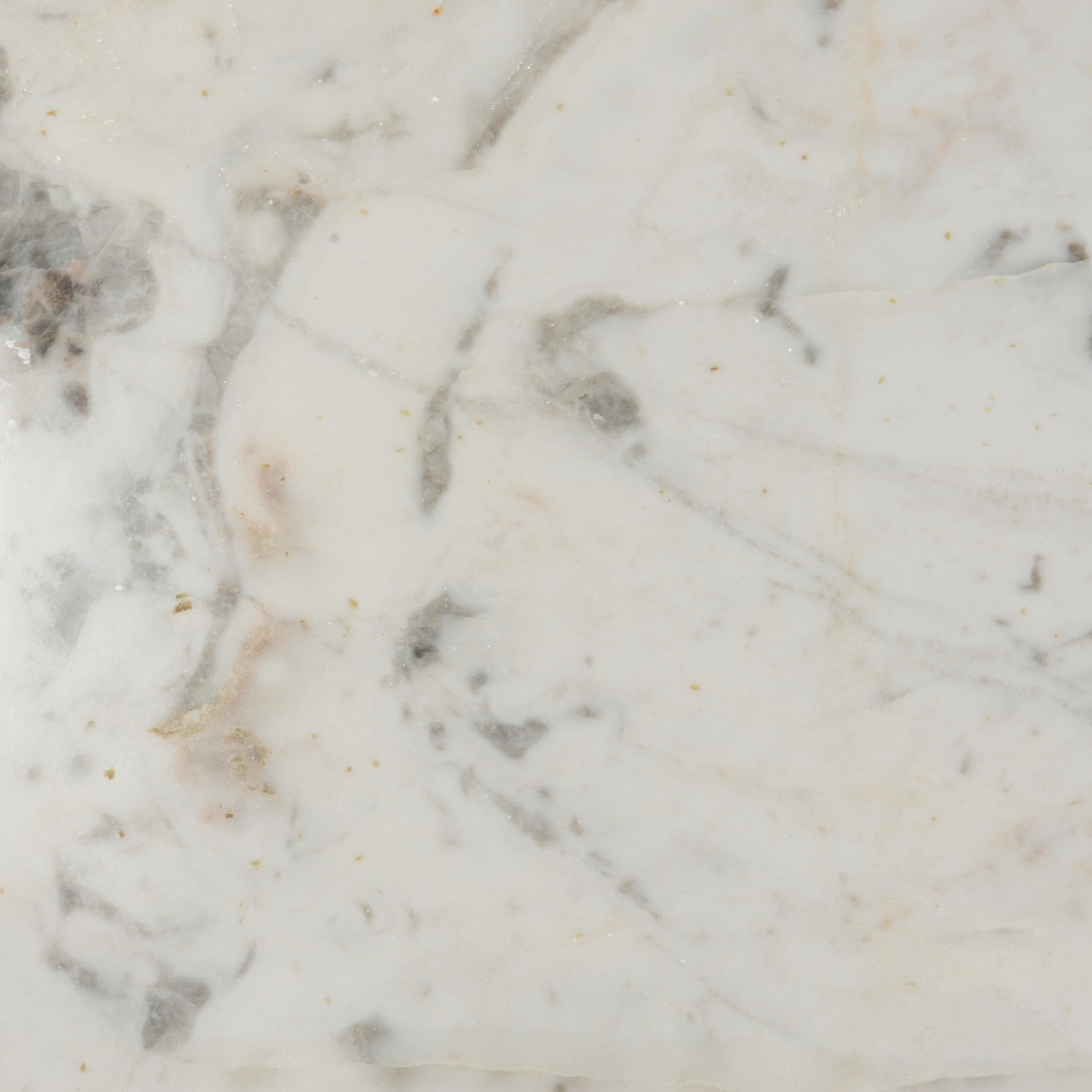 A close-up of a polished white marble surface with soft gray and subtle warm beige veining.