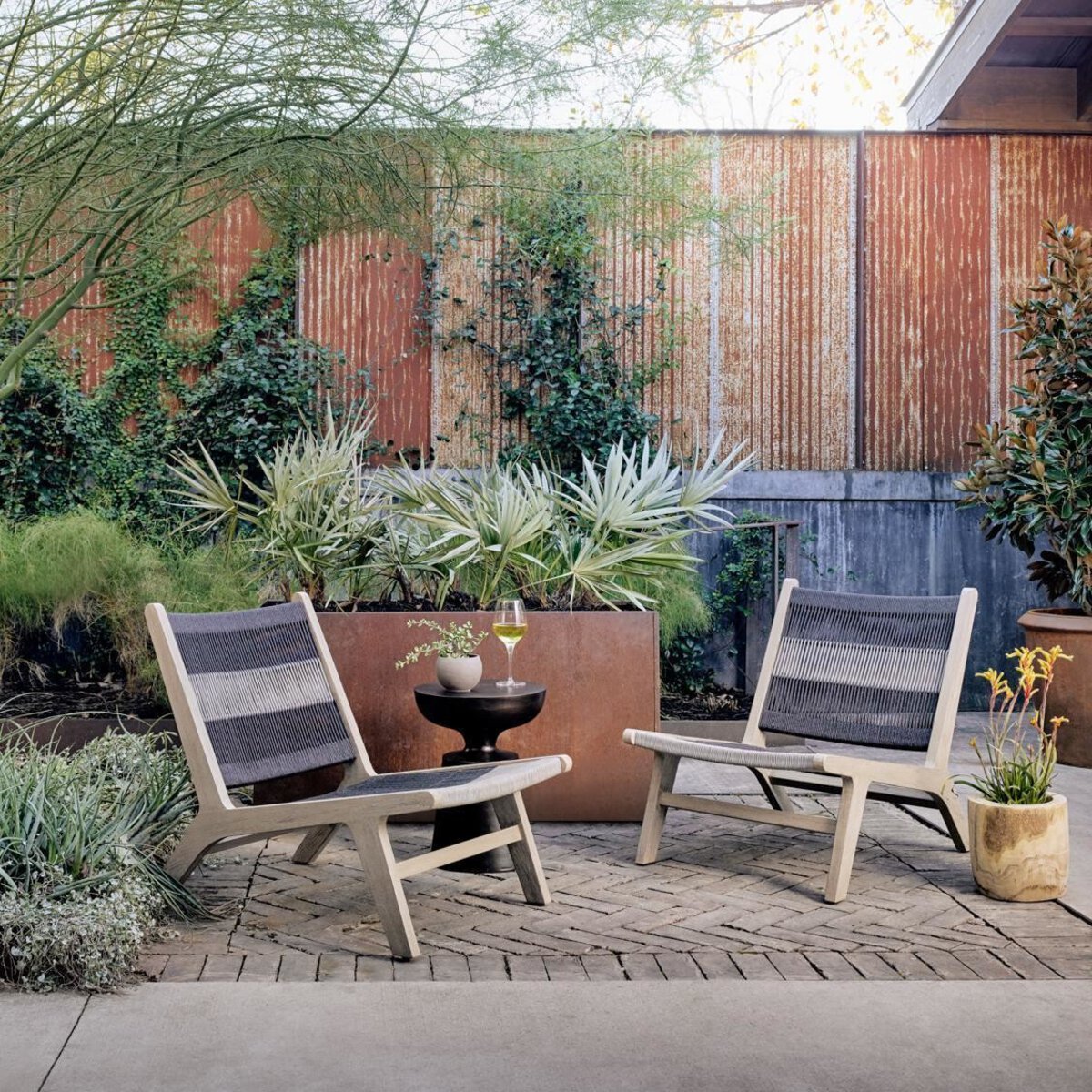Two outdoor chairs with a small table and plants on a patio