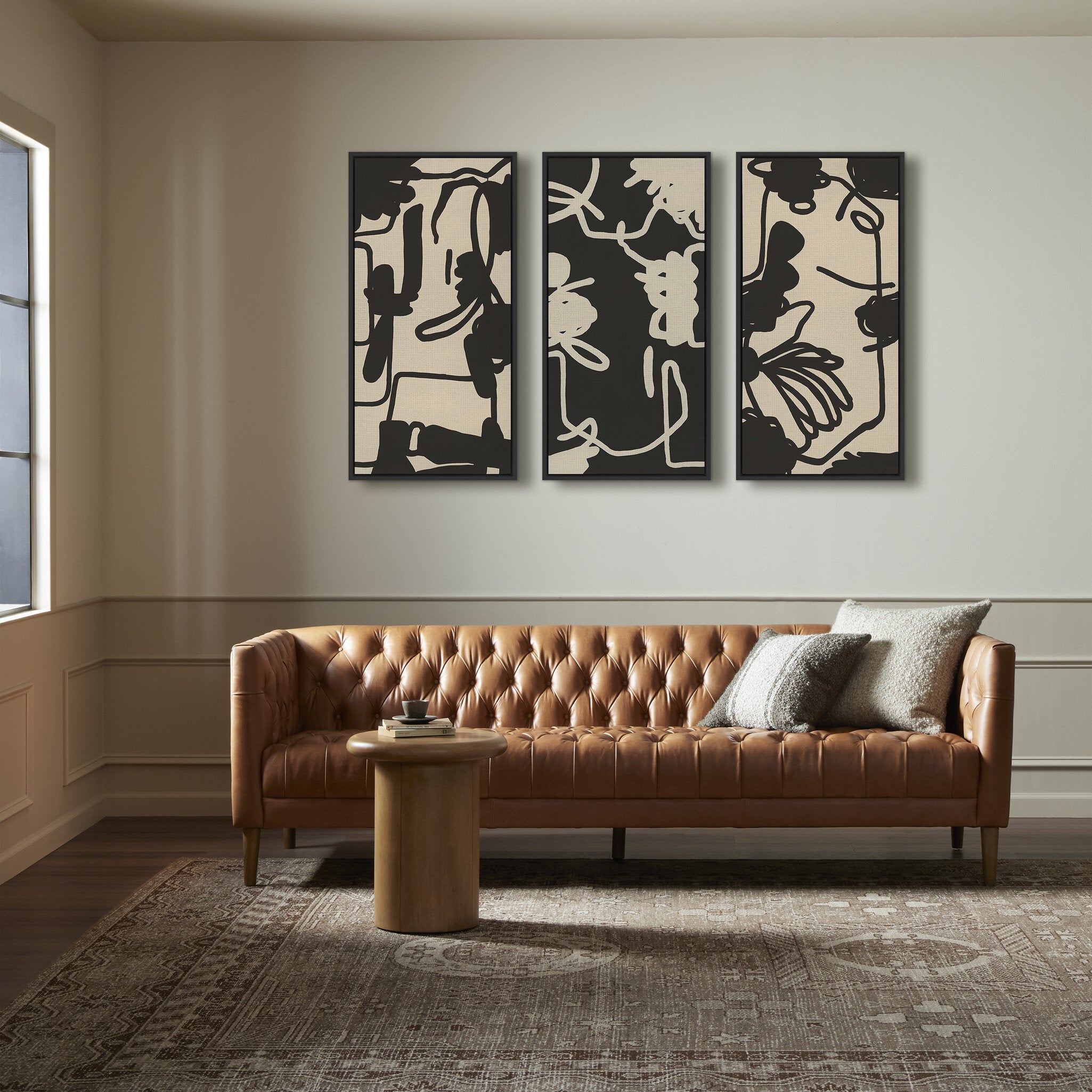 Modern living room with a brown leather sofa, abstract wall art, and a small round table.